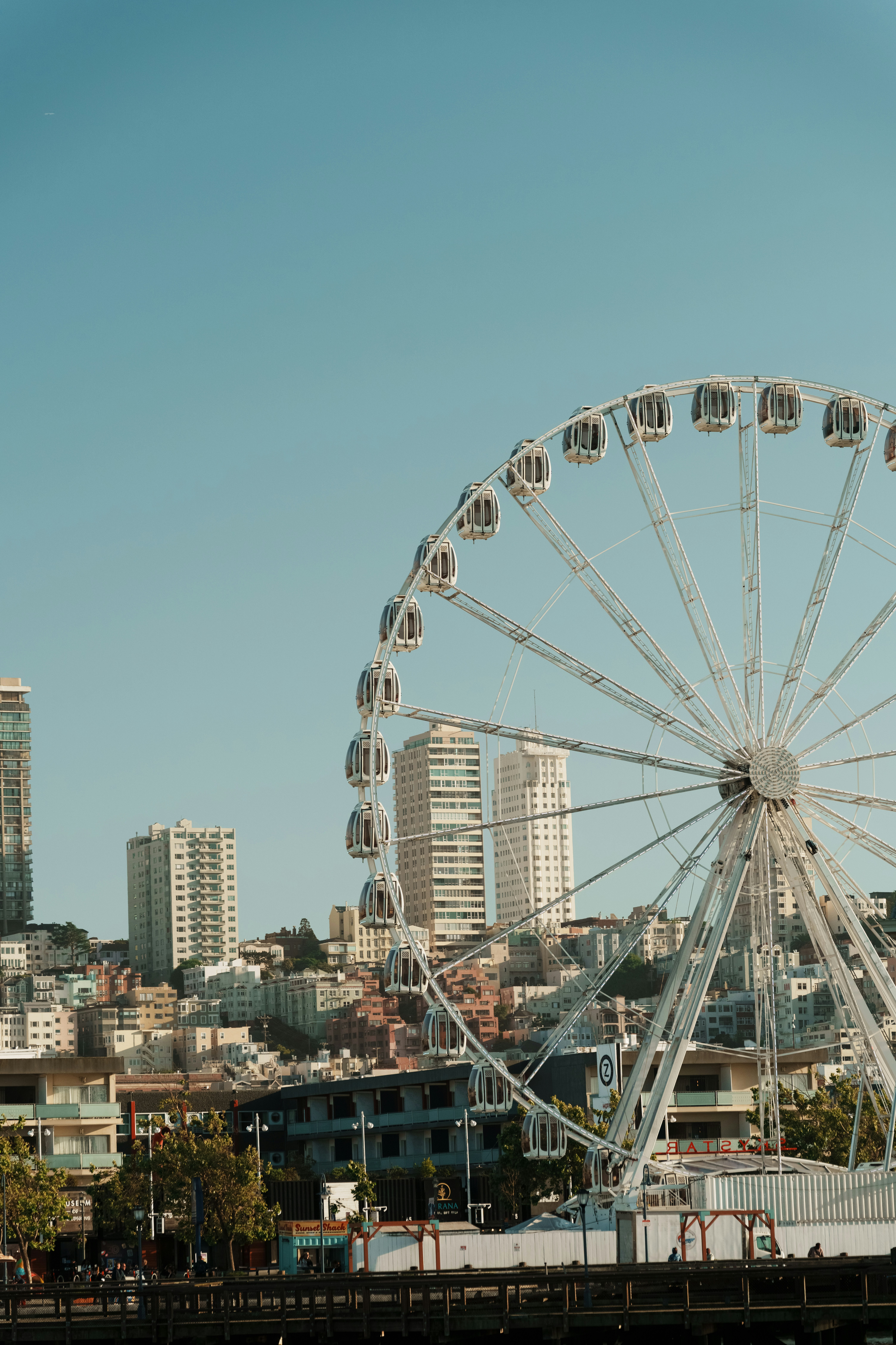White ferris wheel with city buildings in the background.