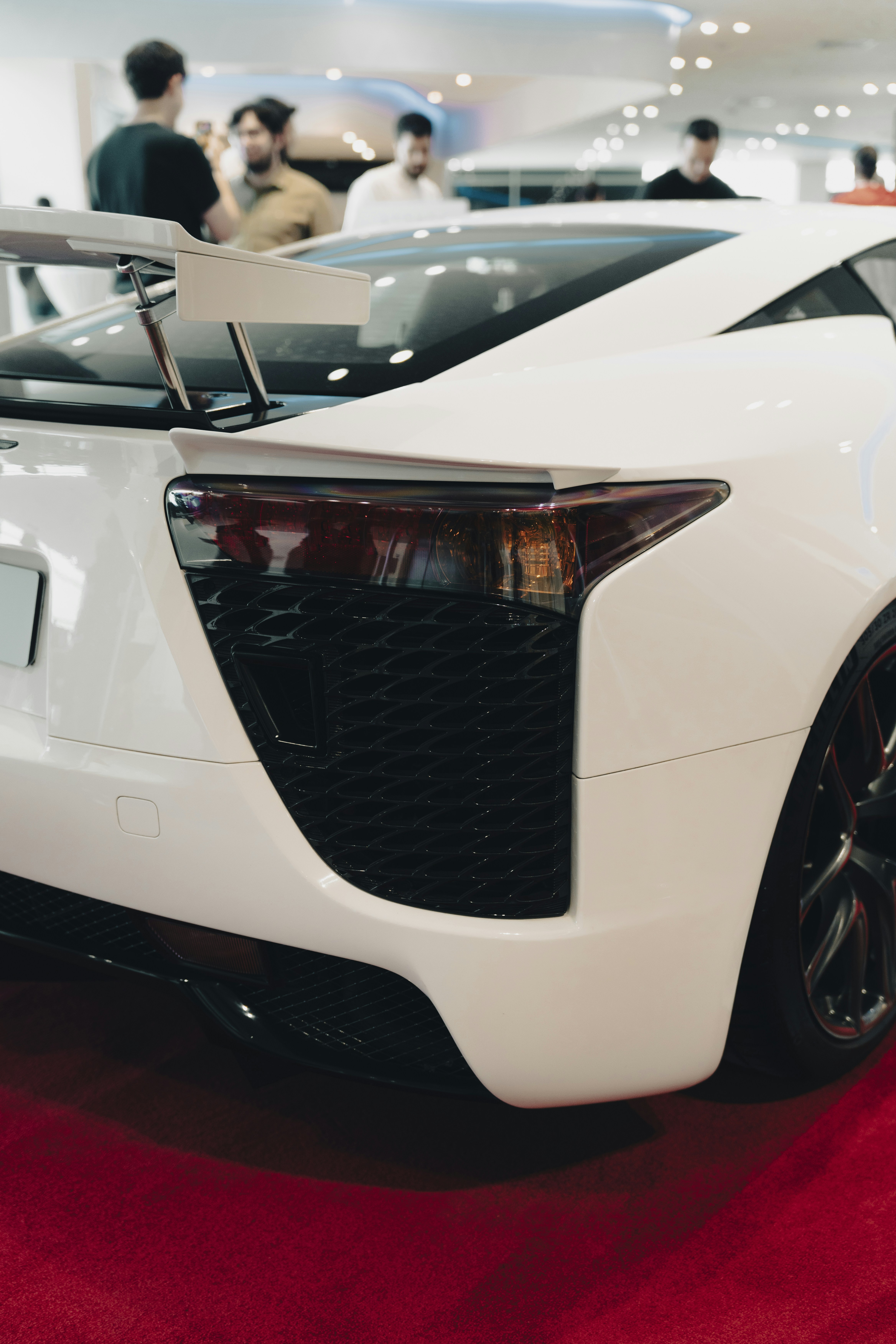 Voiture de sport blanche avec aileron sur tapis rouge
