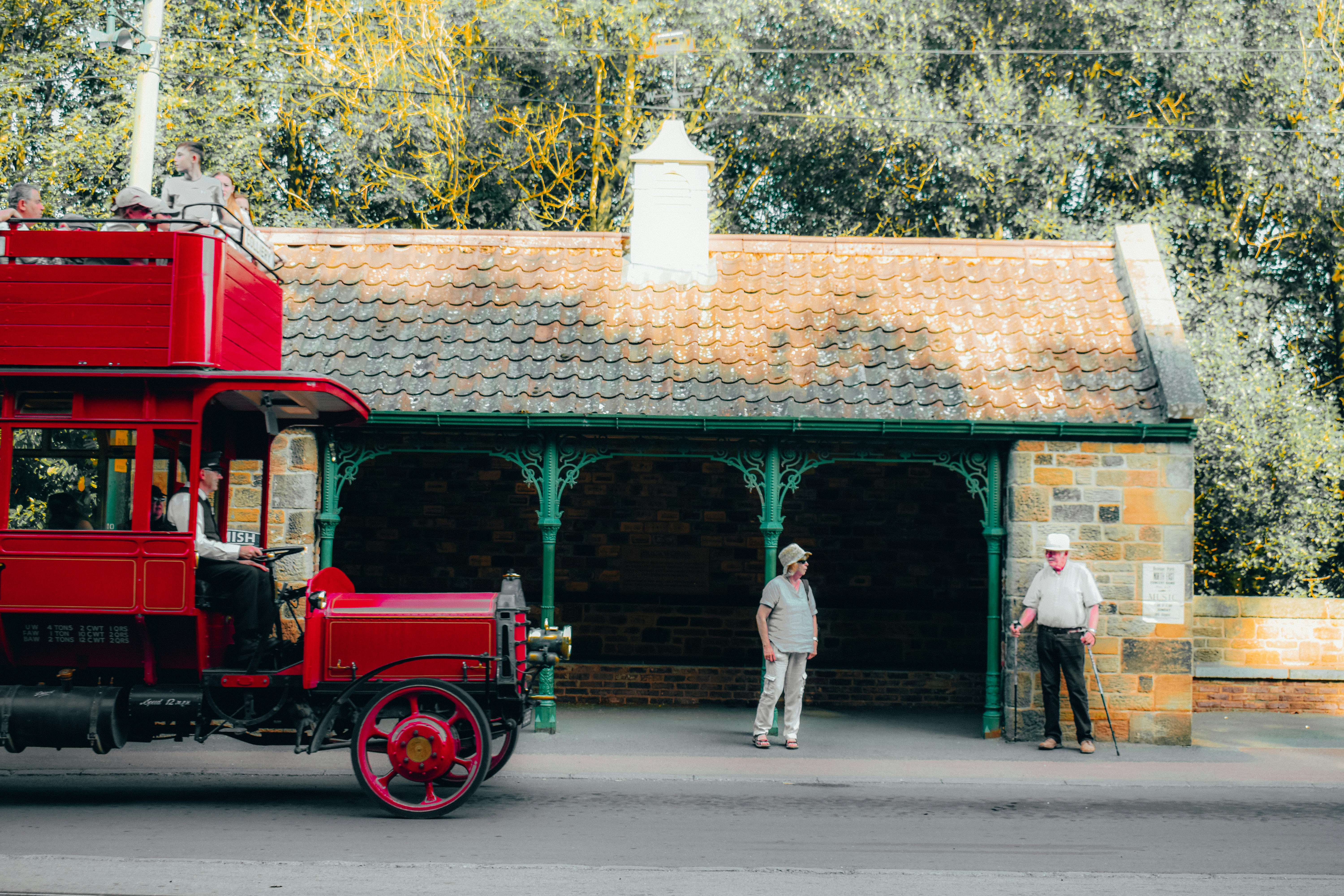 Vintage red bus parked near a stone building