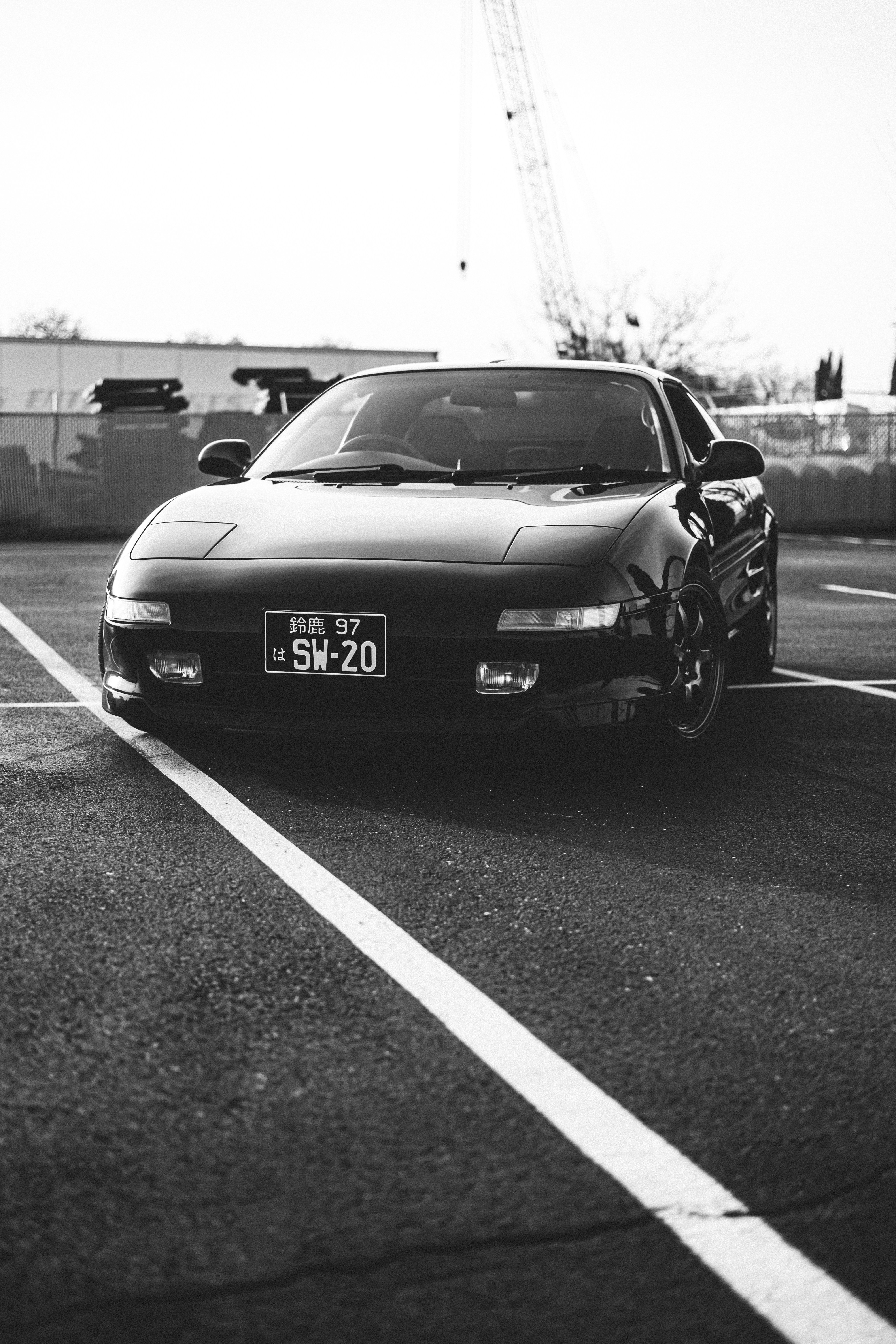 Voiture de sport noire garée sur l’asphalte avec des lignes blanches.