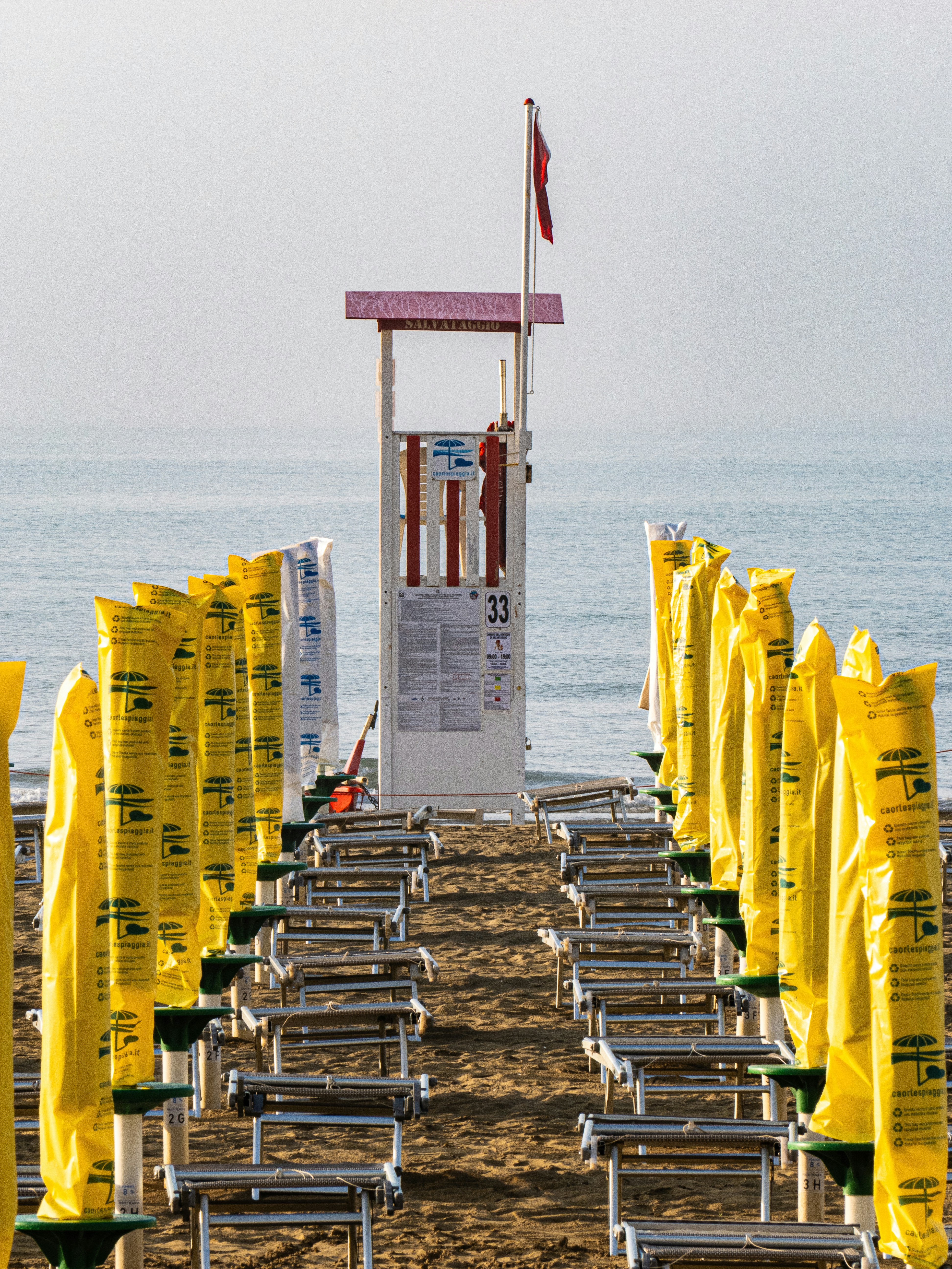 Filas de tumbonas de playa cubiertas de amarillo y torre de socorrismo