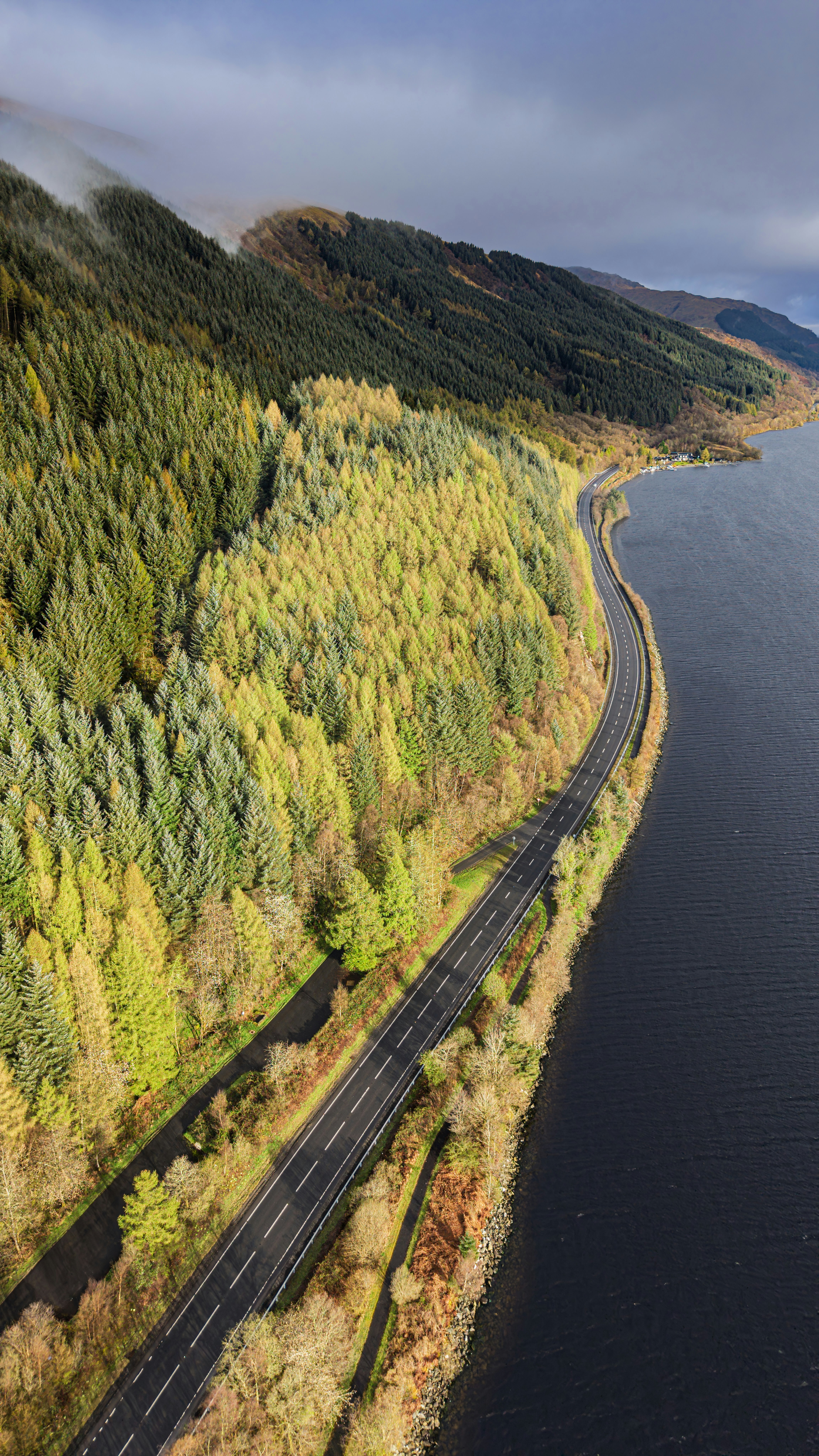 Straße entlang eines riesigen Sees und bewaldeter Berge
