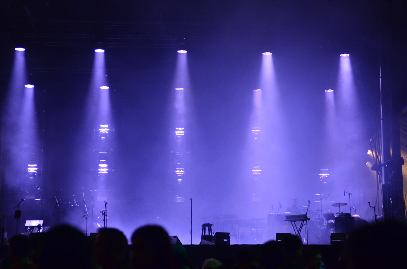 Des faisceaux bleus et violets éclairent une scène de concert.
