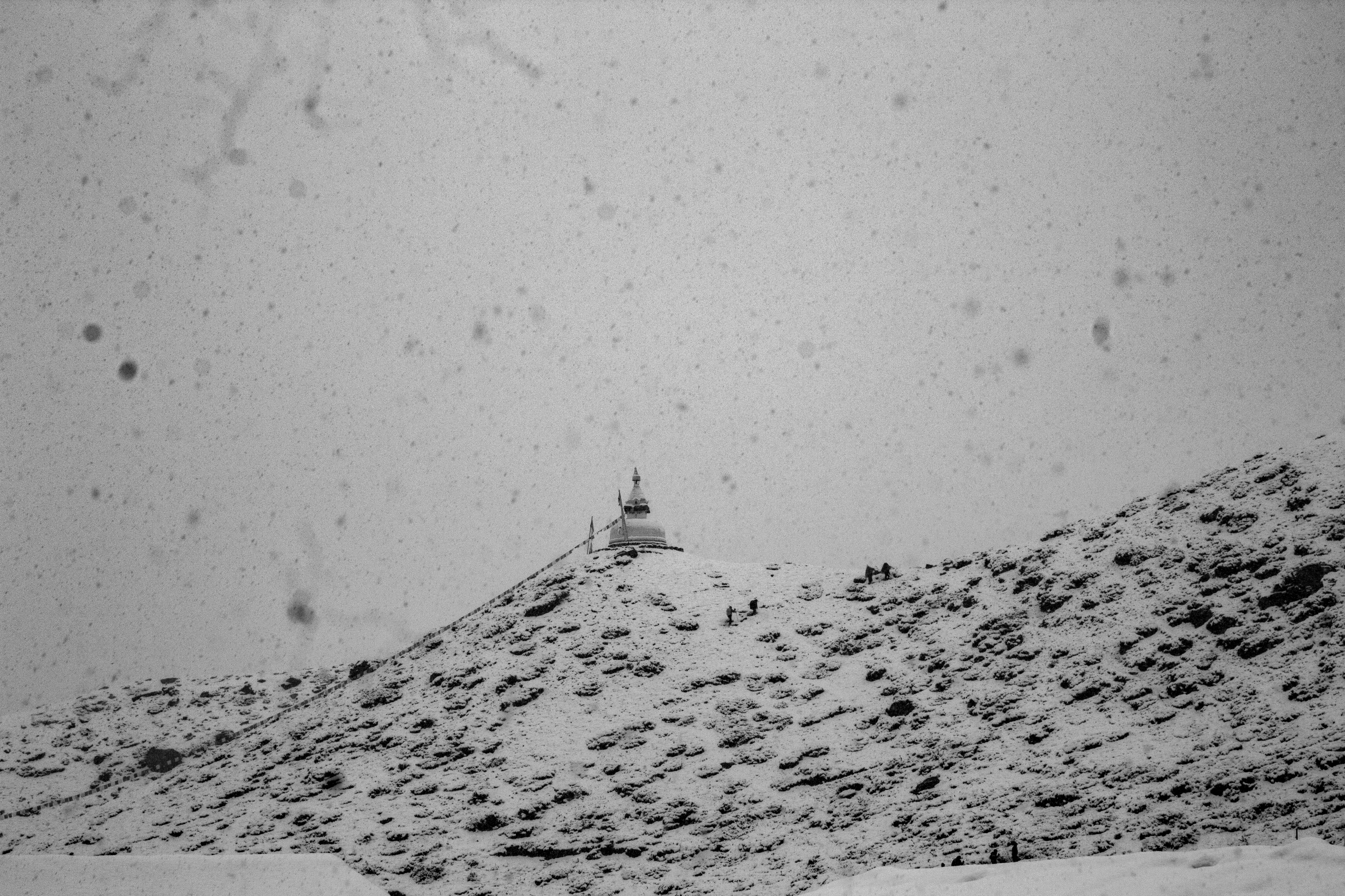 Une structure isolée se dresse au sommet d’une montagne enneigée.