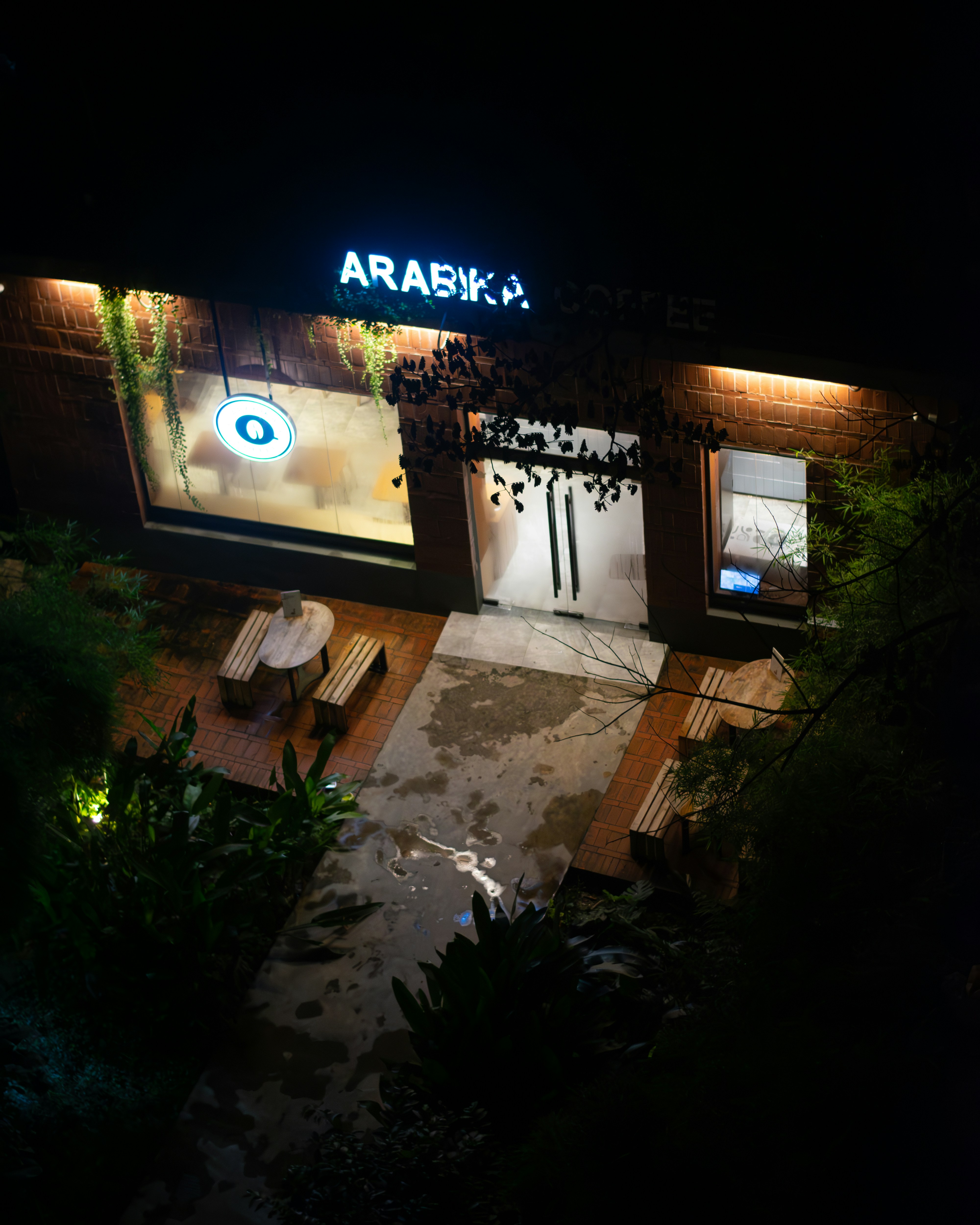 Eksterior kafe Arabika di malam hari dengan tempat duduk luar ruangan