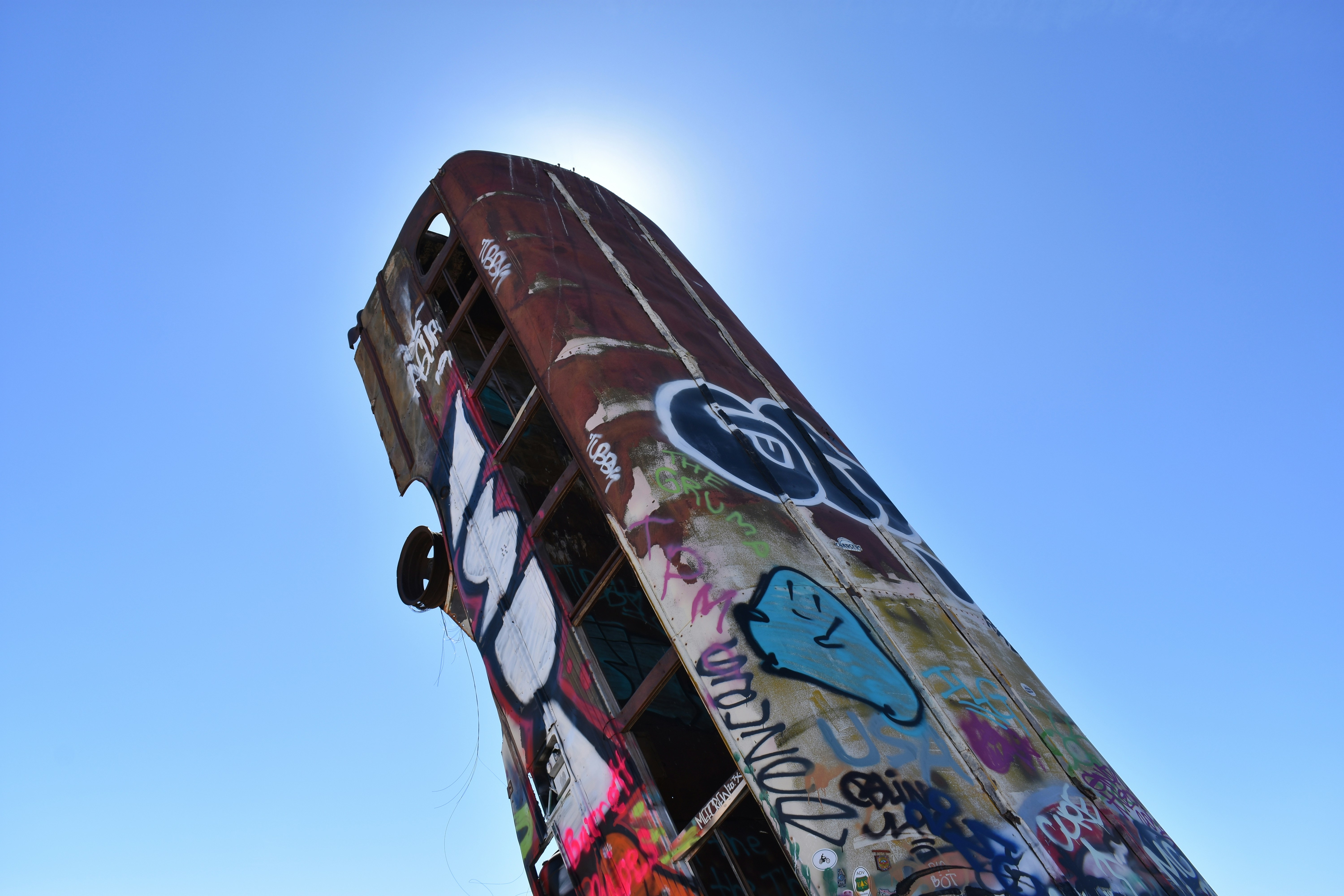 Graffiti-covered train car against a bright blue sky.