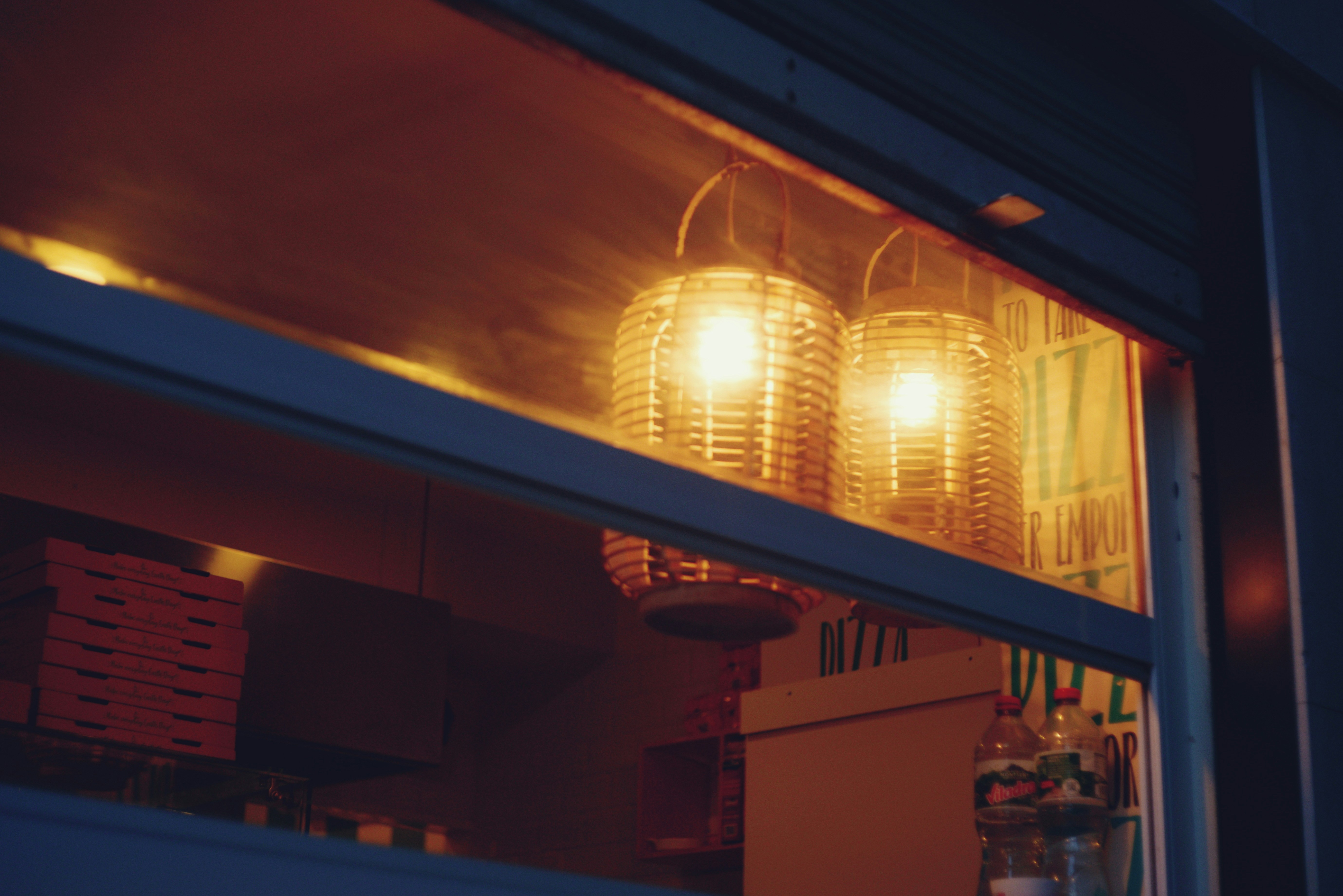 Two woven lamps glow warmly inside a building.