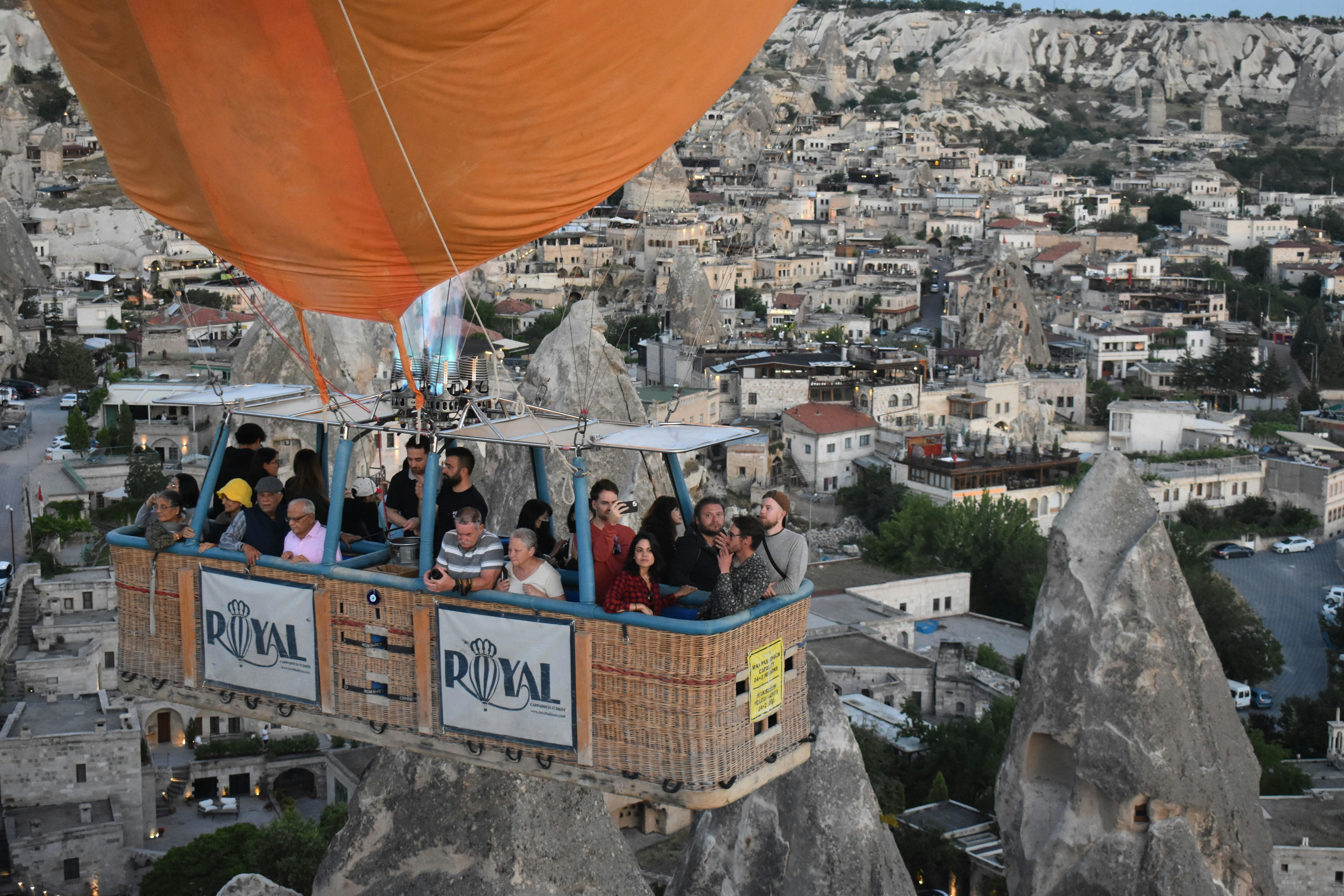 Hot air balloon carrying passengers over rocky landscape