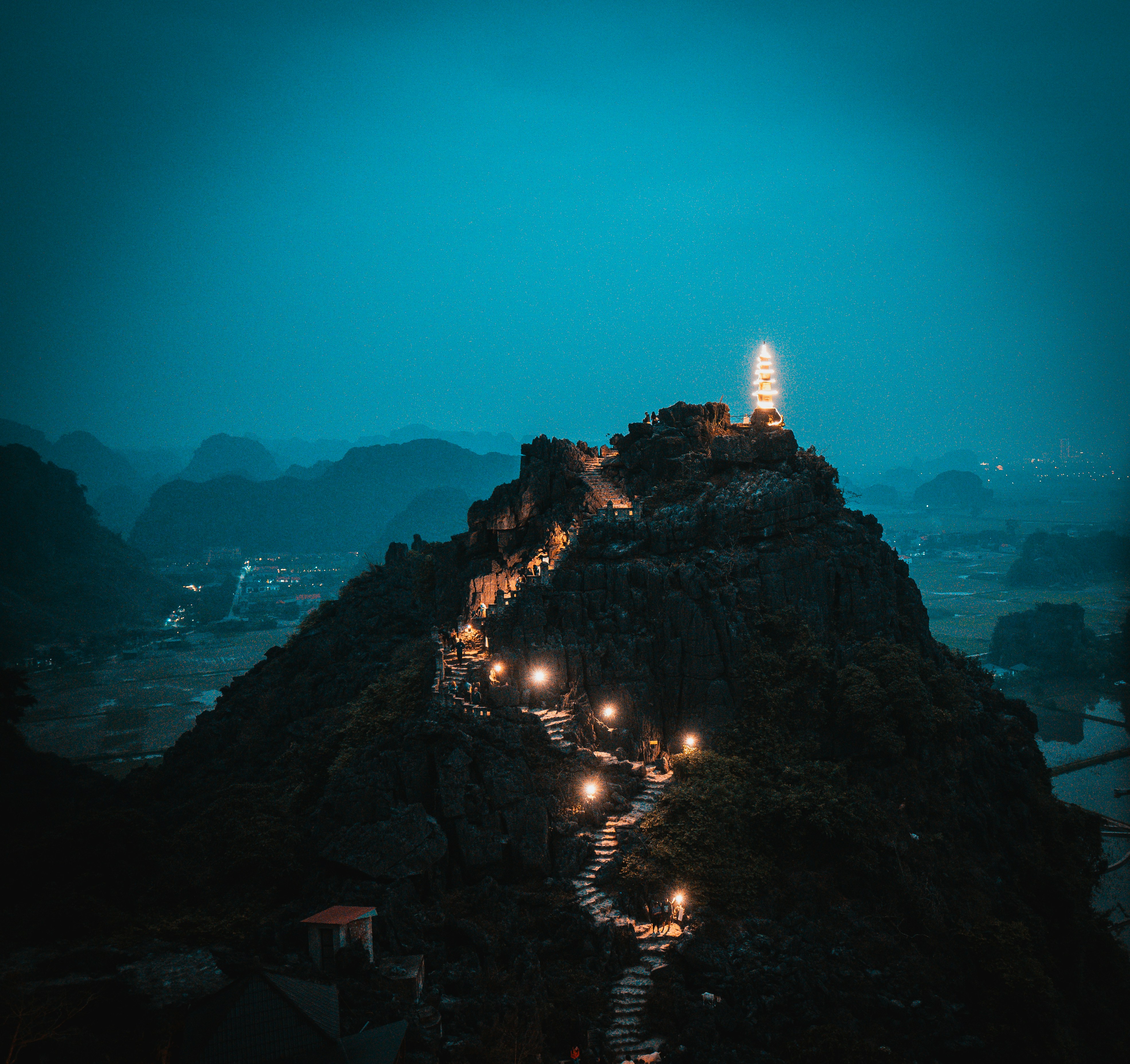A winding staircase illuminated by lights leads up a mountain.