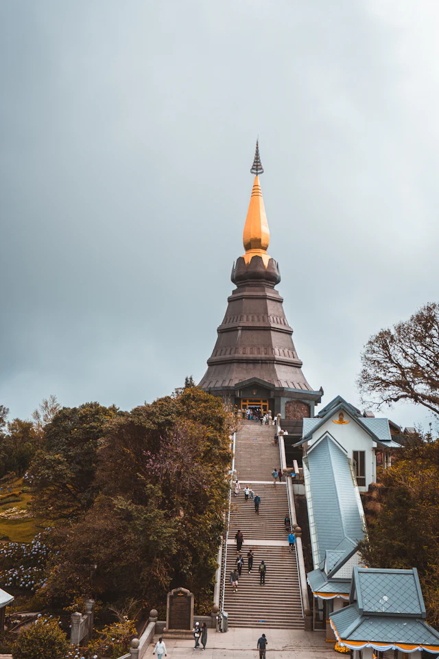 One of Doi Inthanon's twin royal chedis rising above a long stairway on the misty mountaintop, its golden spire catching the light.