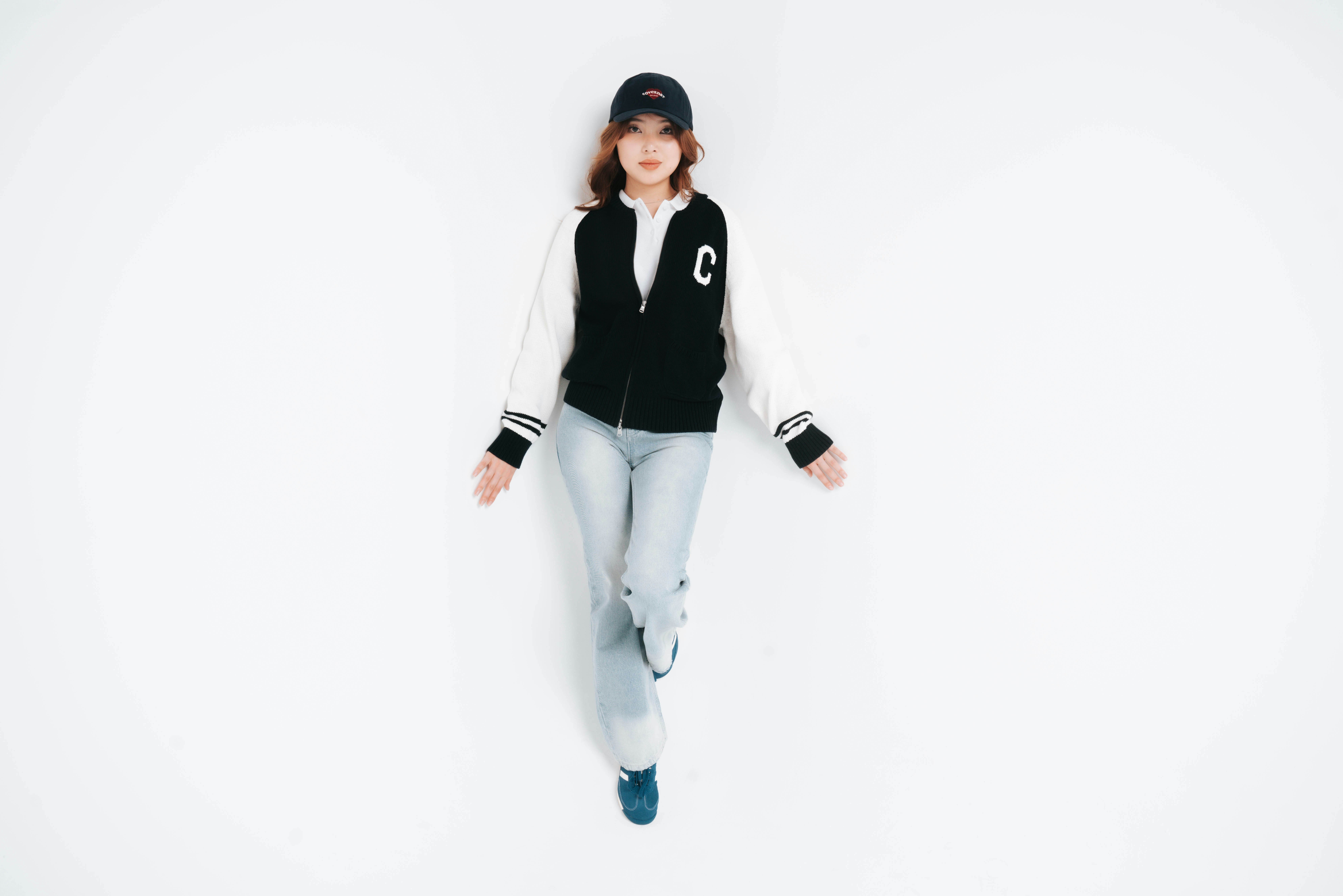 Young woman in baseball cap and varsity jacket