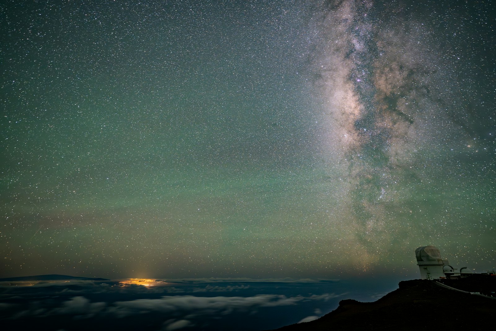The Milky Way arcing over a mountaintop observatory dome at night