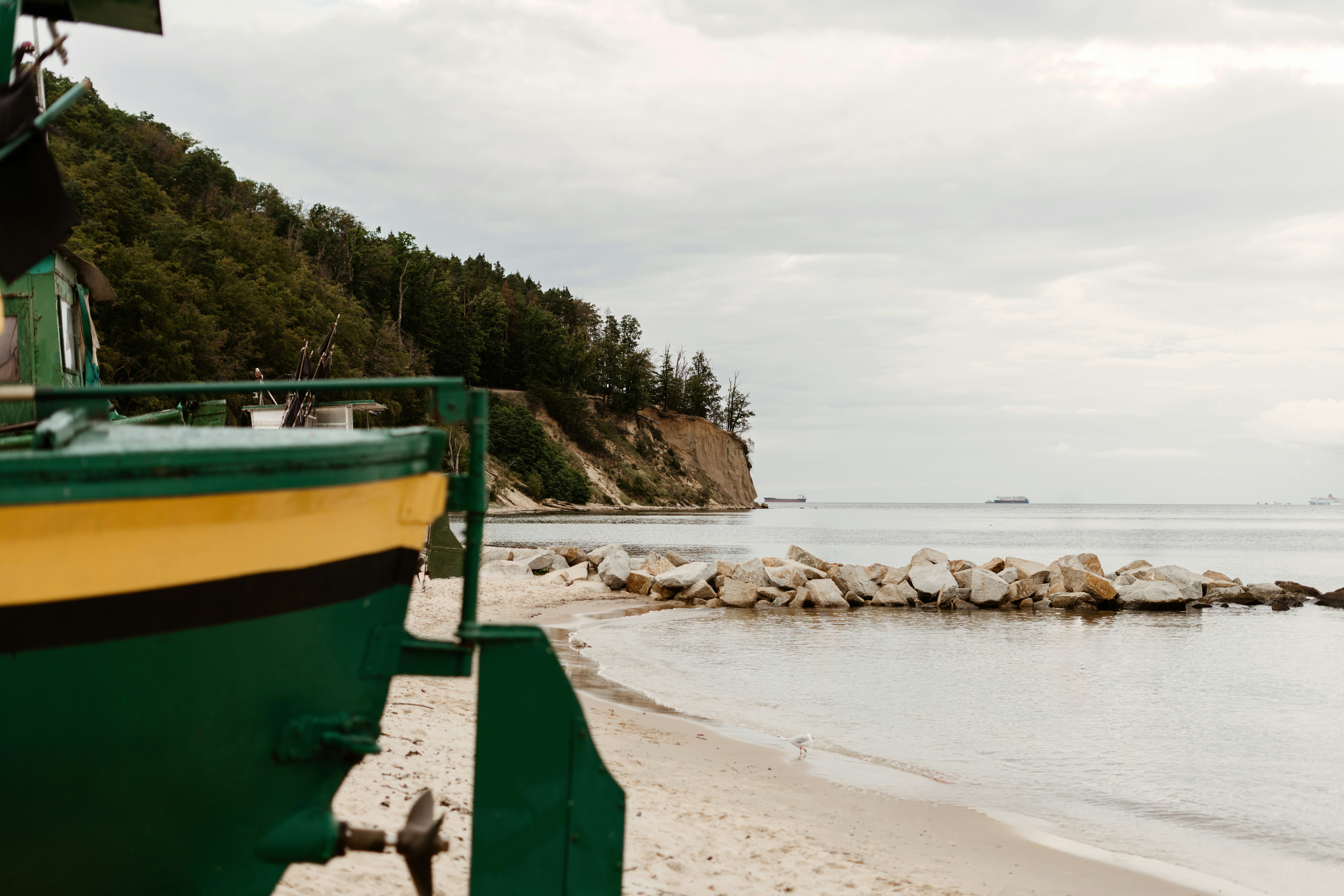 Perahu hijau di pantai berpasir dengan pantai berbatu.