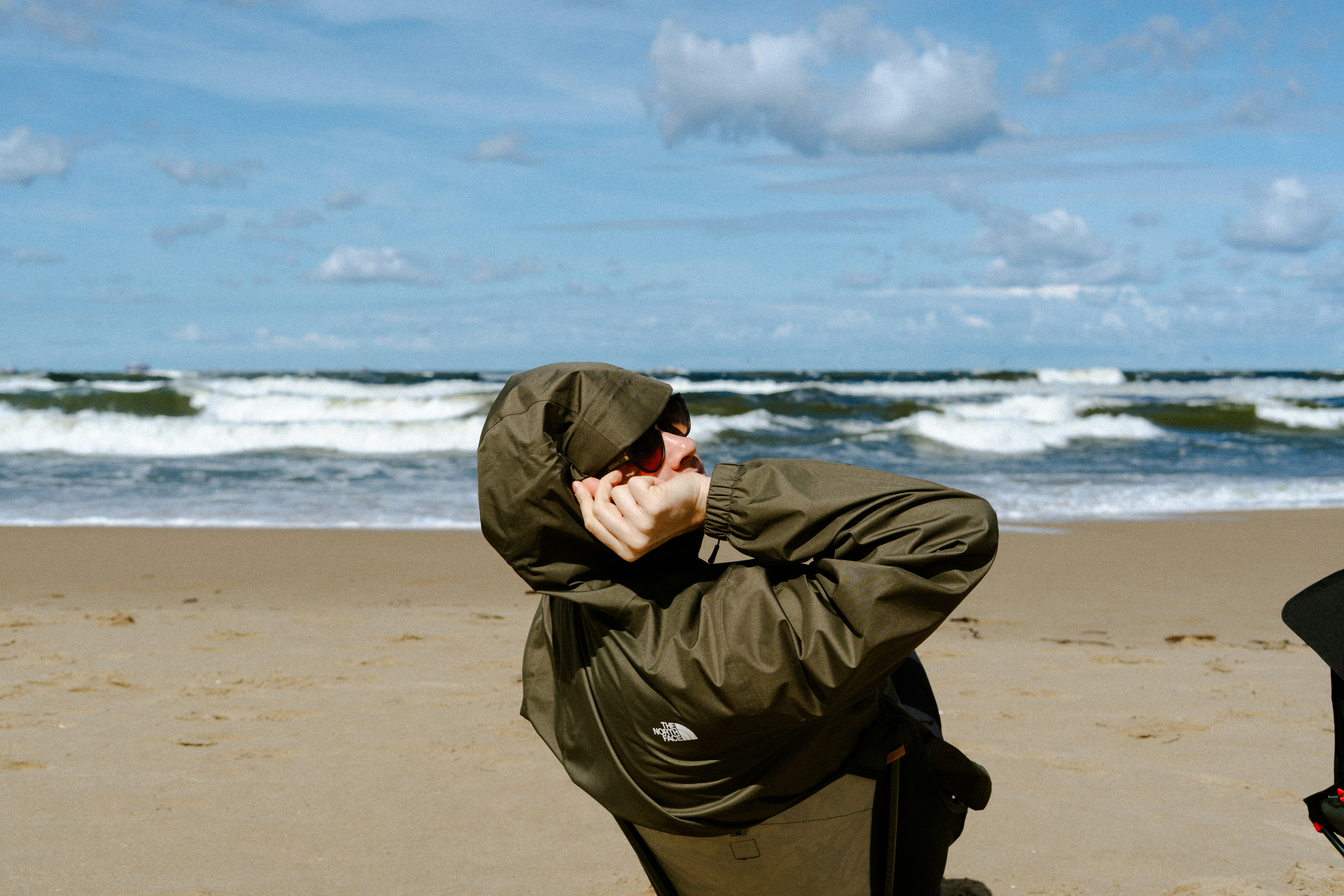 Orang dengan jaket berkerudung di pantai yang berangin.