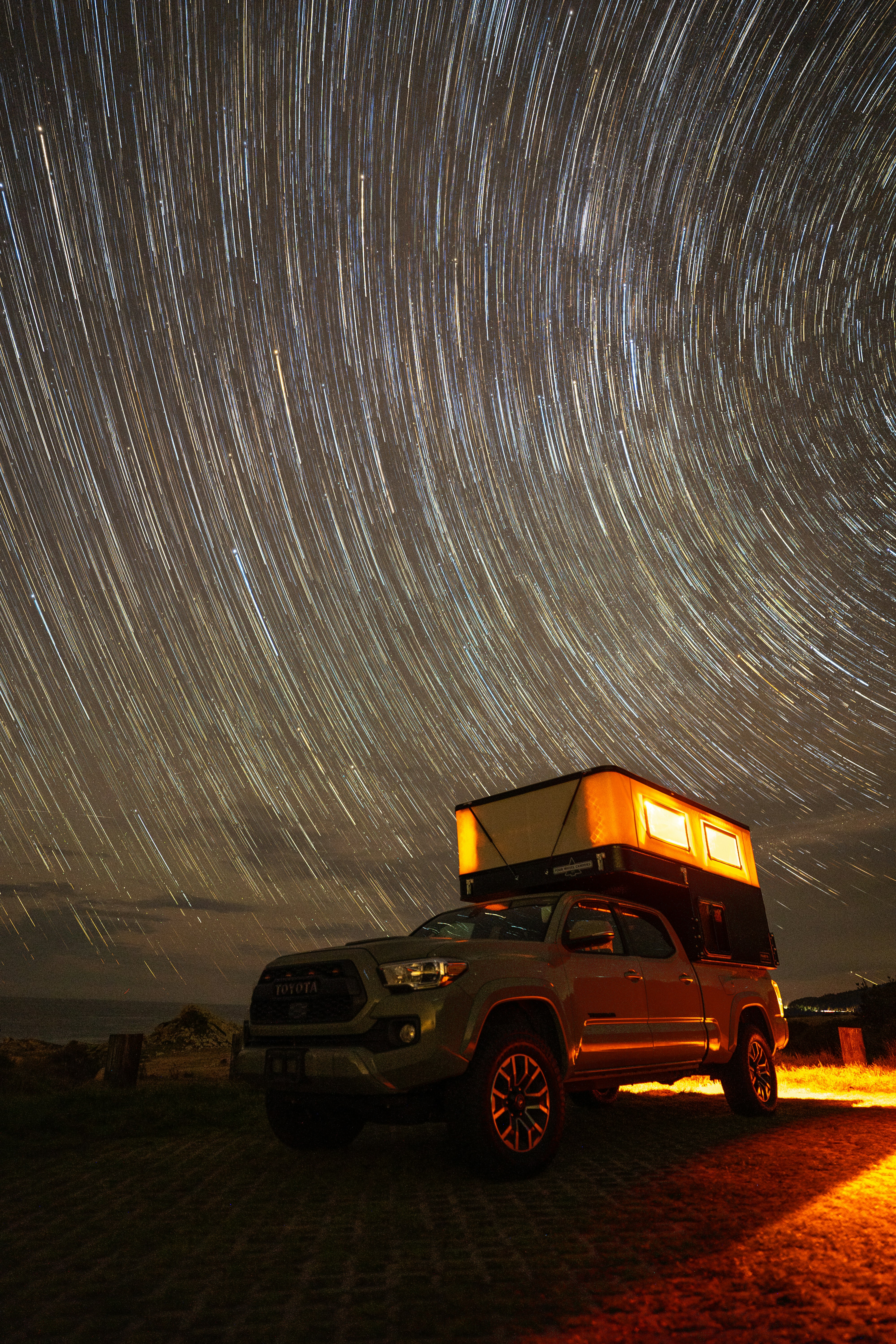 Photo of Truck with rooftop tent under star trails at night by Josh Williams