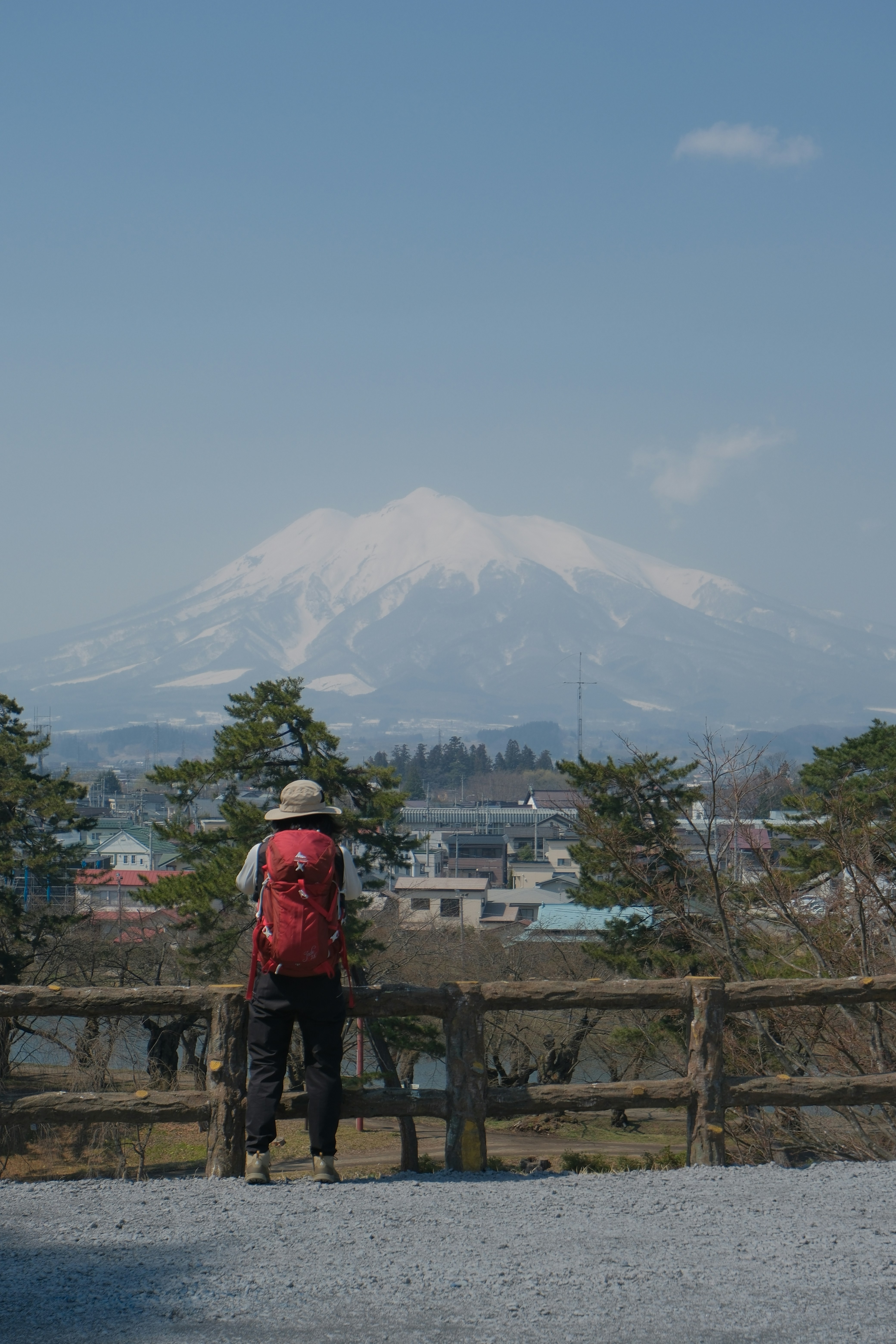 Hiker with red backpack views snow-capped mountain.
