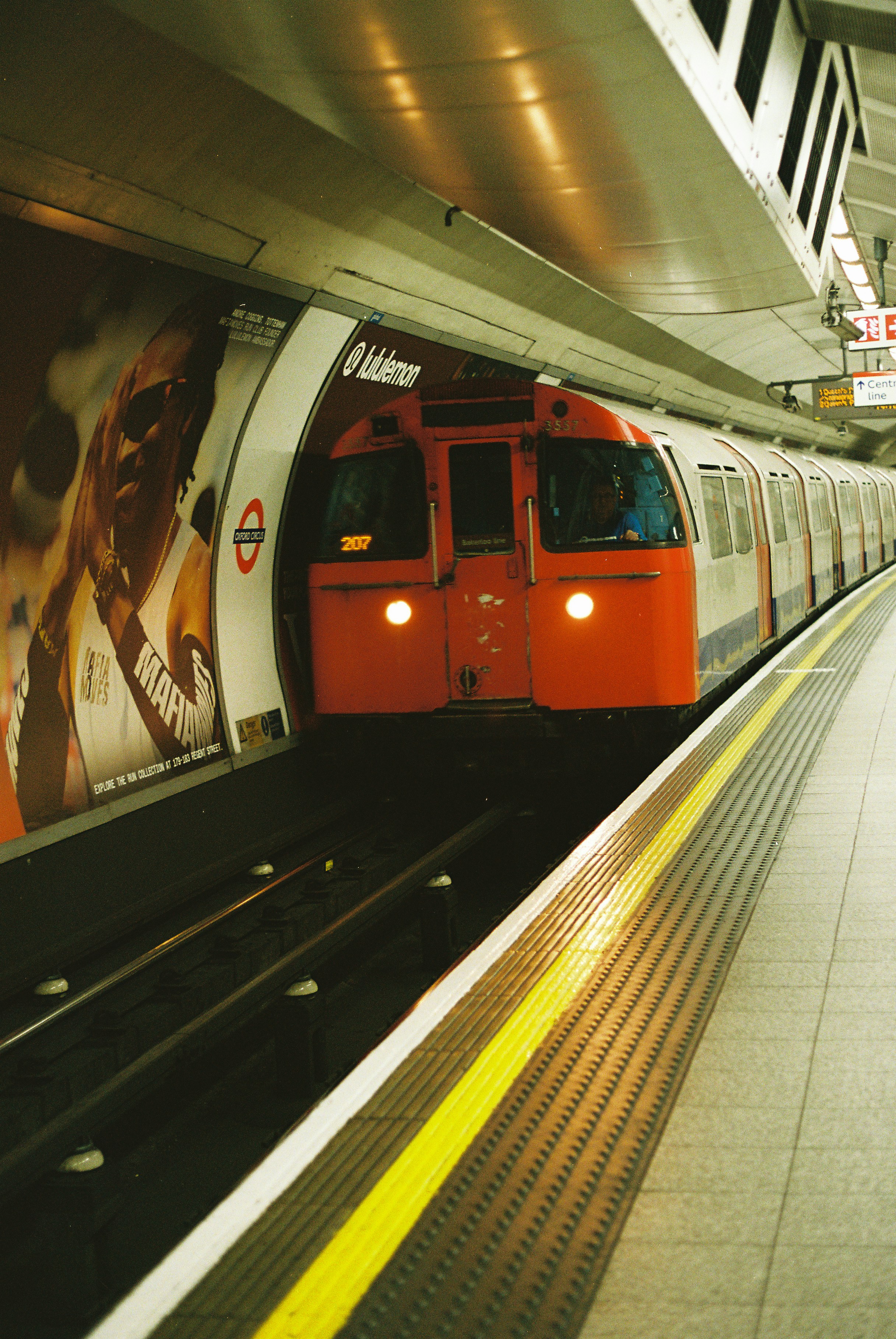 An orange and white subway train arrives at a station.