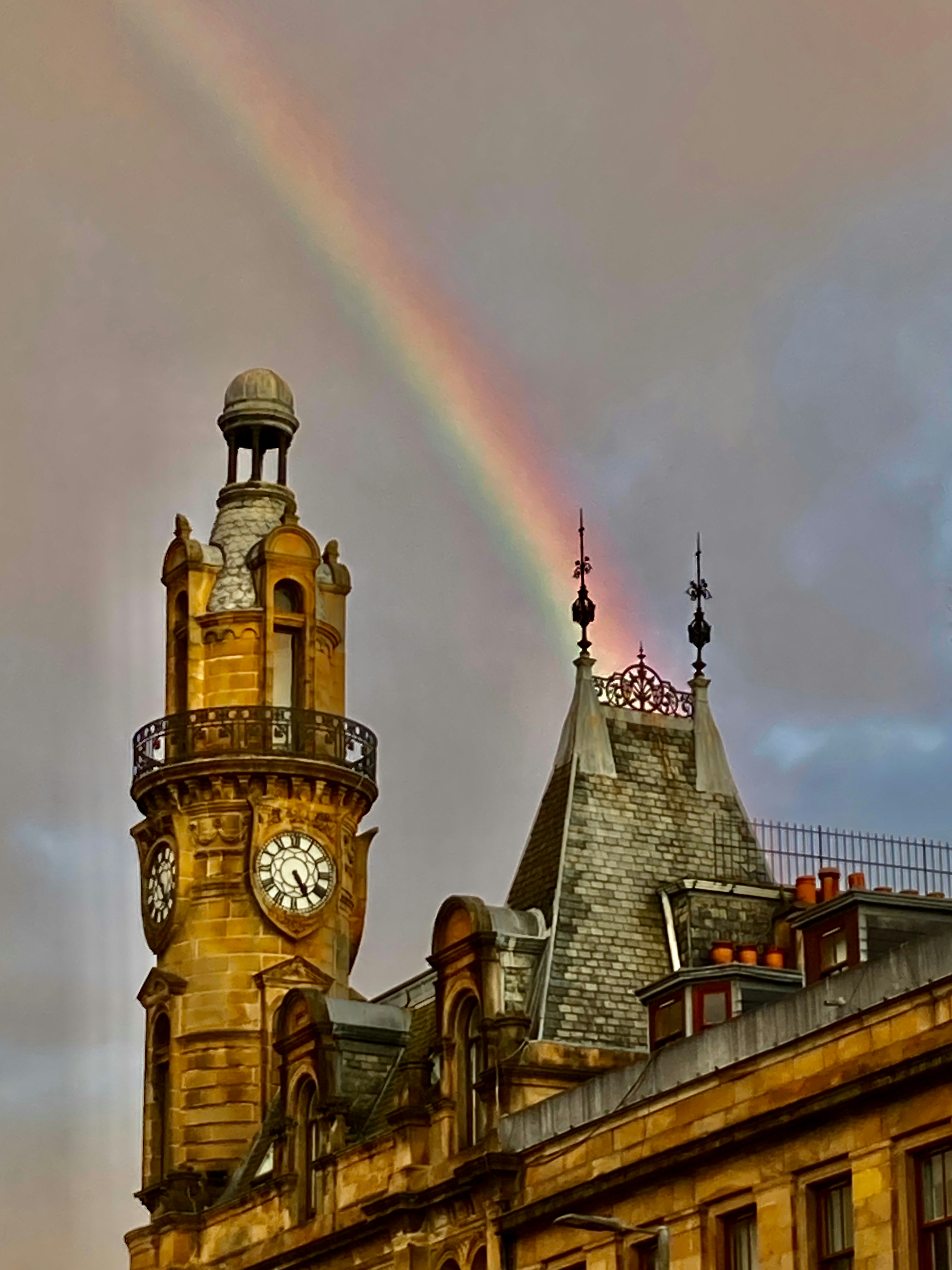 Arc-en-ciel au-dessus d’un bâtiment historique avec une tour d’horloge.