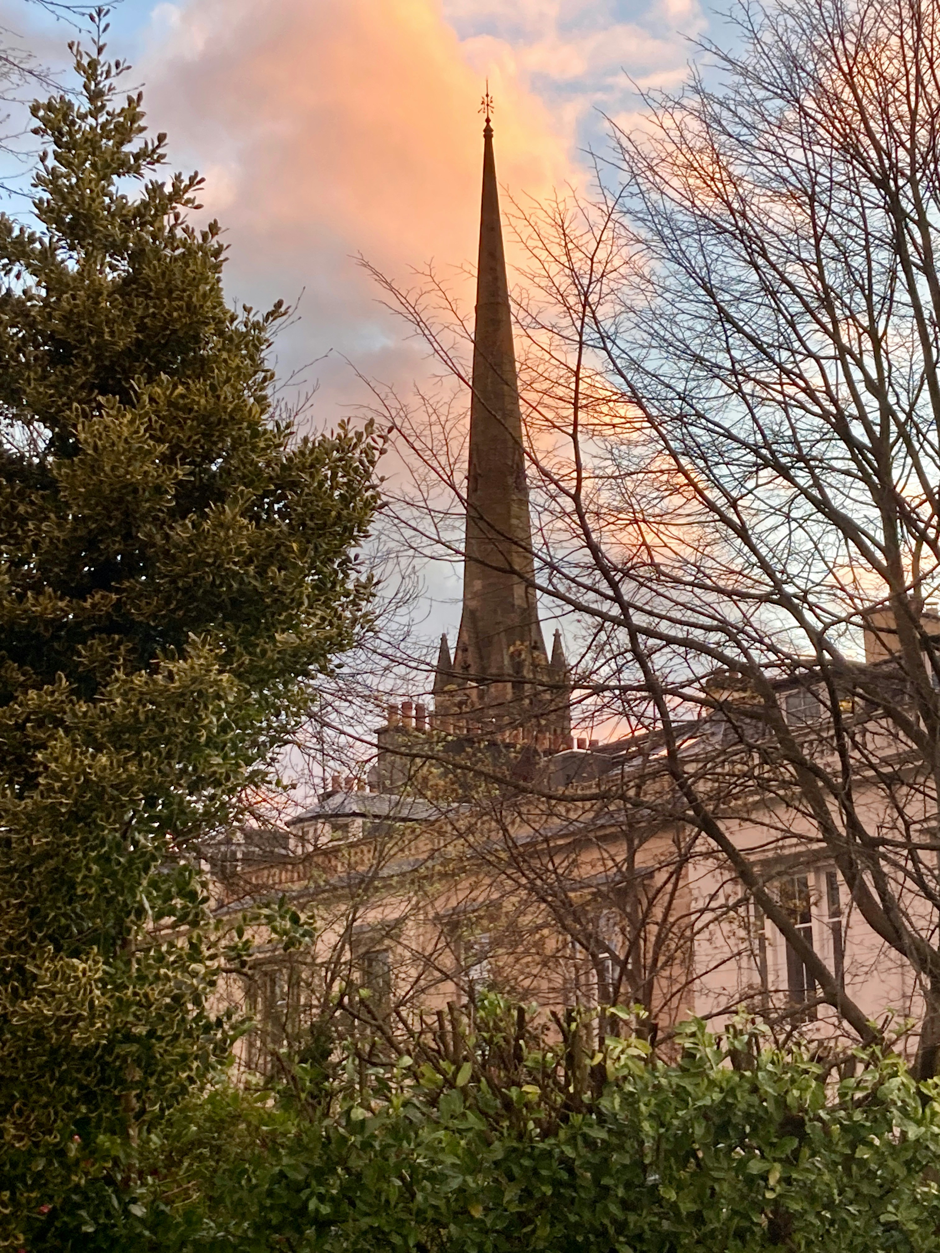 Flèche de l’église vue à travers les arbres au coucher du soleil