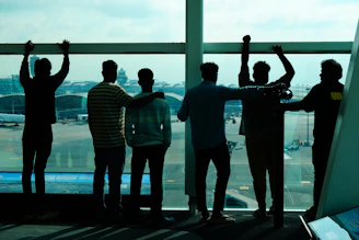 Group of friends looking out airport window at planes