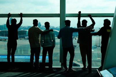 Group of friends looking out airport window at planes