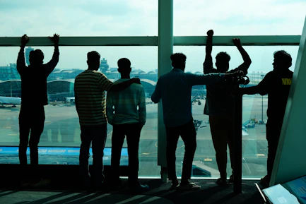 Group of friends looking out airport window at planes