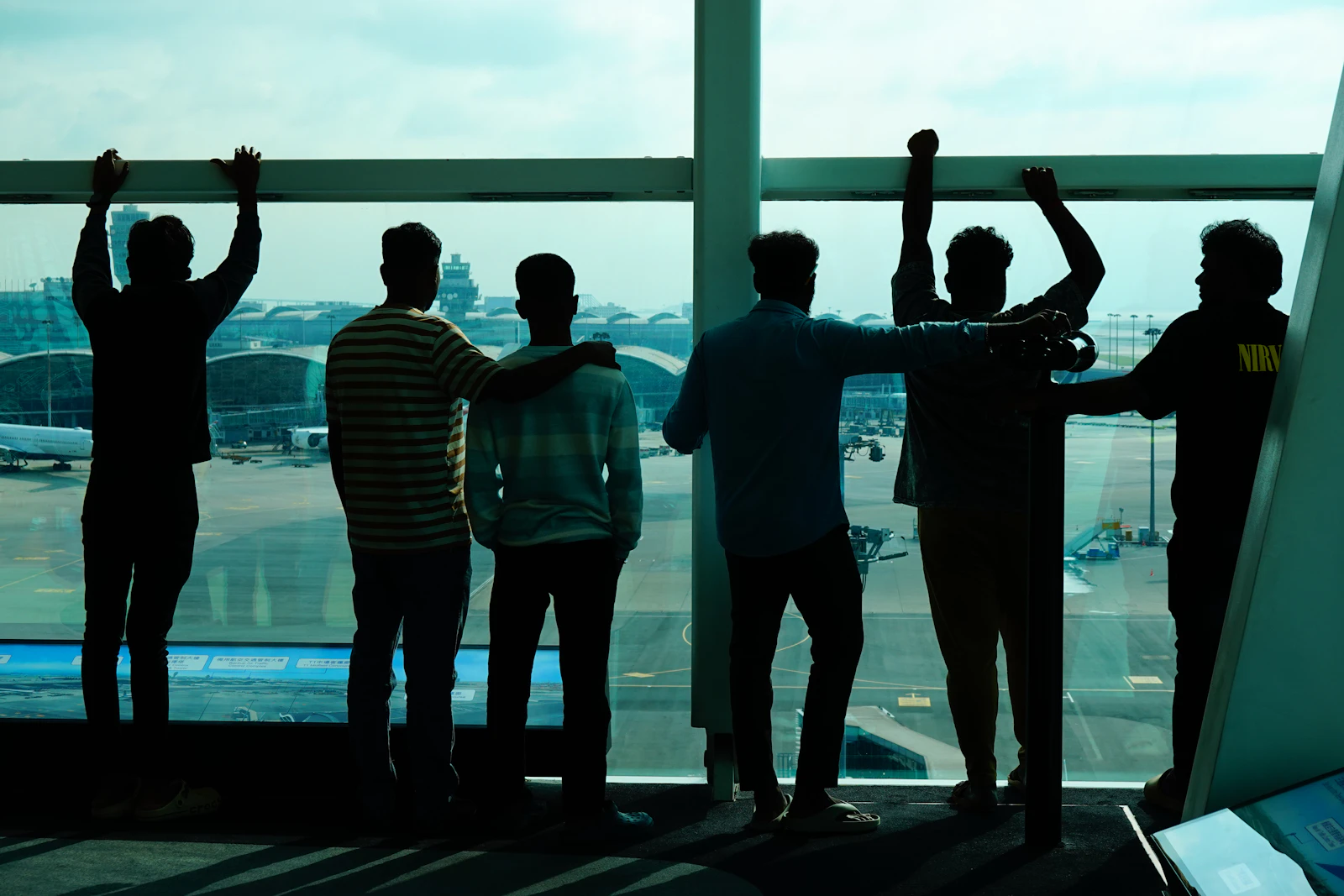 A group of friends together at an airport window before departing from different home cities for a shared trip
