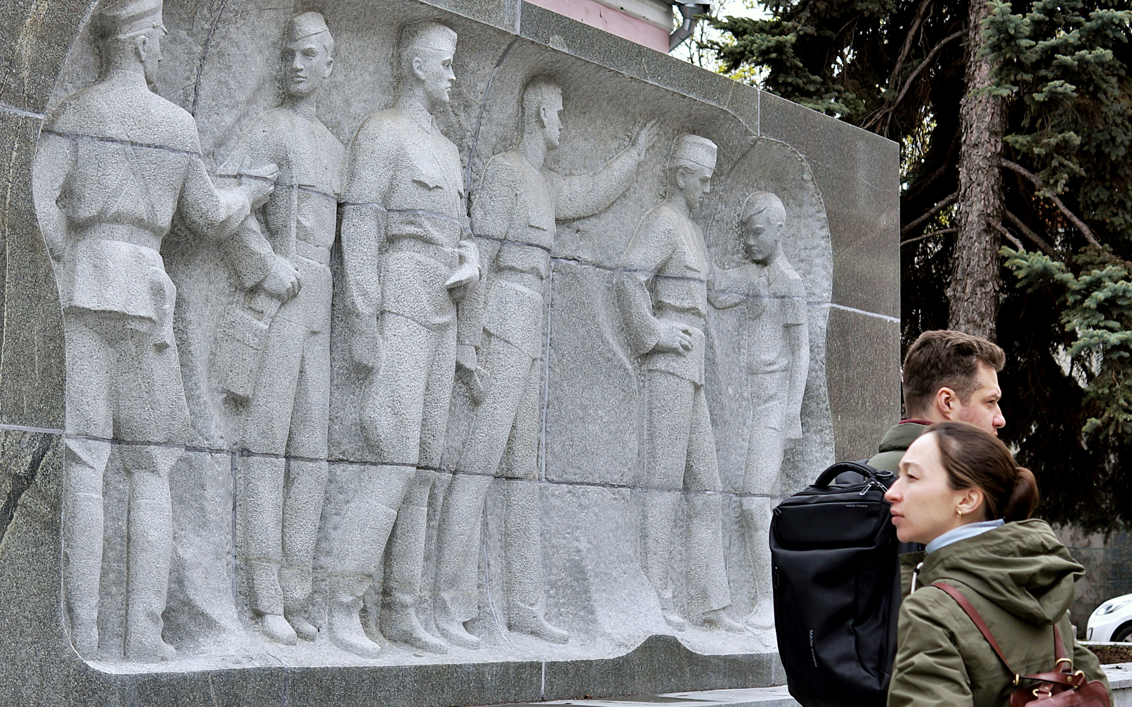 People observe a stone relief of soldiers