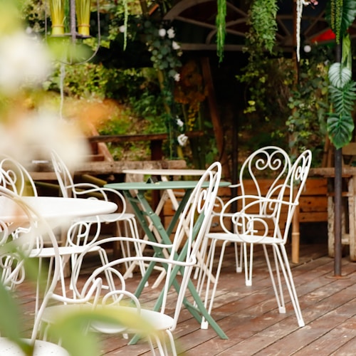 Weisse Bistrostühle und kleiner Tisch in einem Garten
