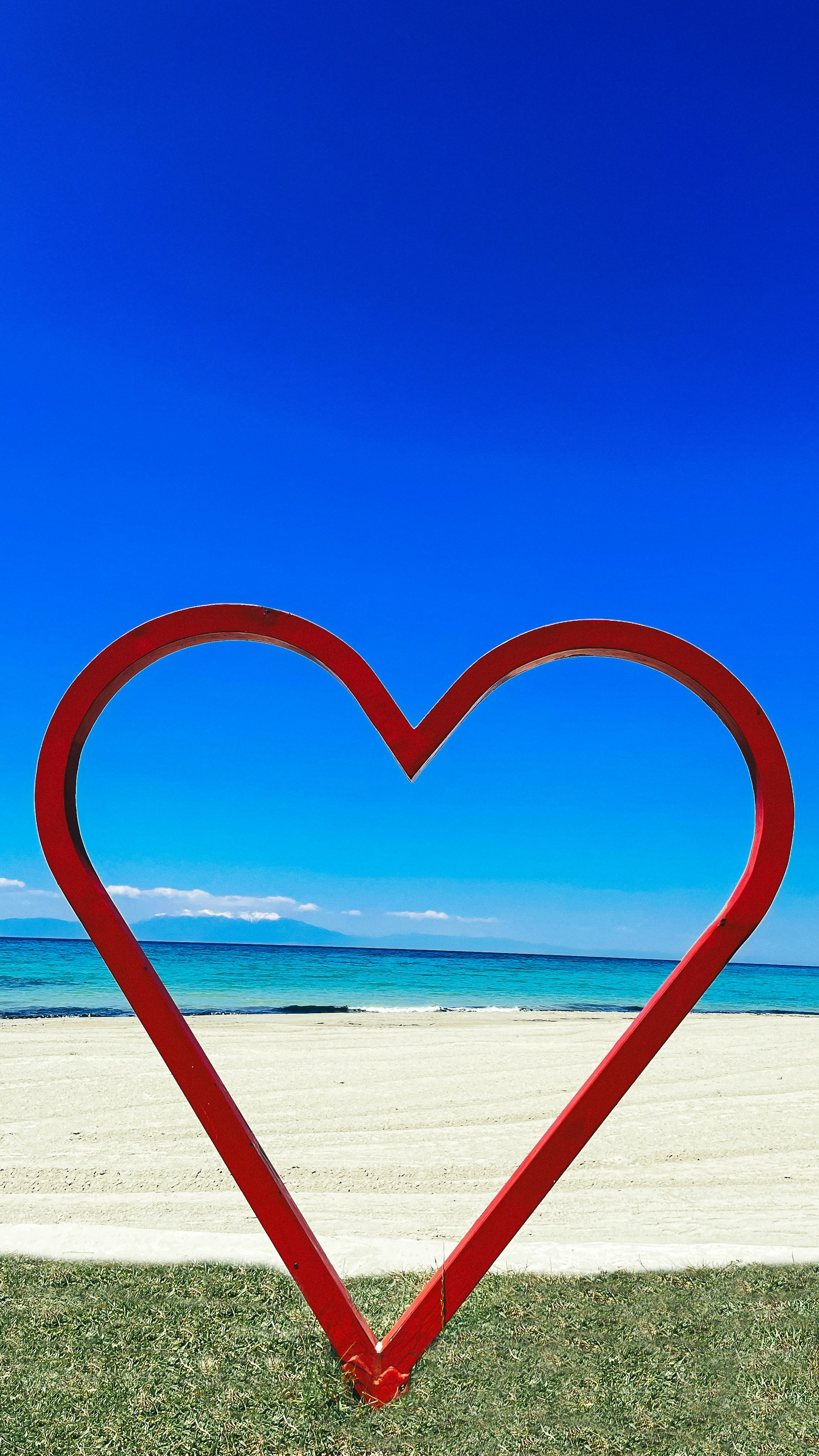 Bingkai hati merah di pantai dengan langit biru