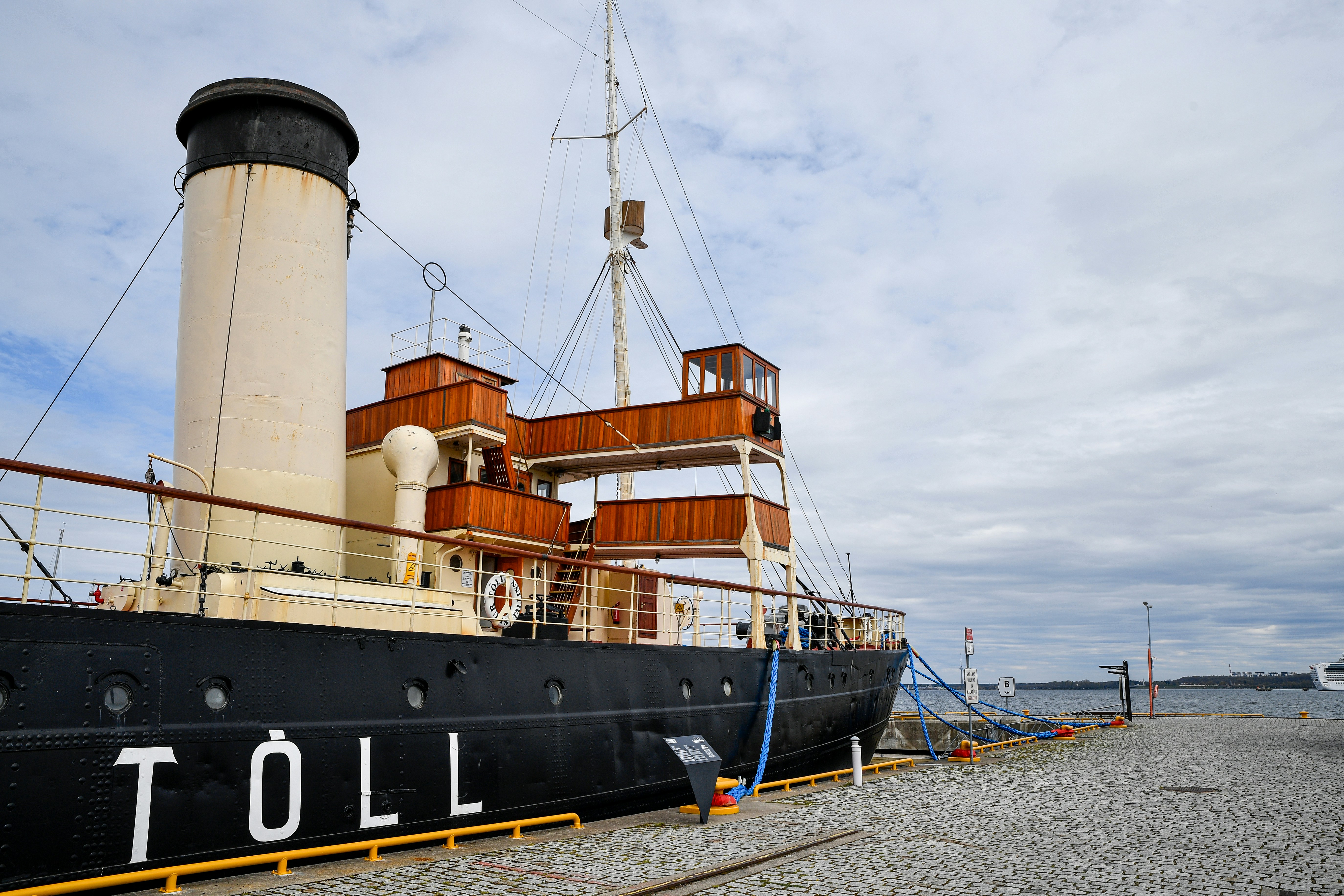 A vintage steamship named toll docked by a pier.