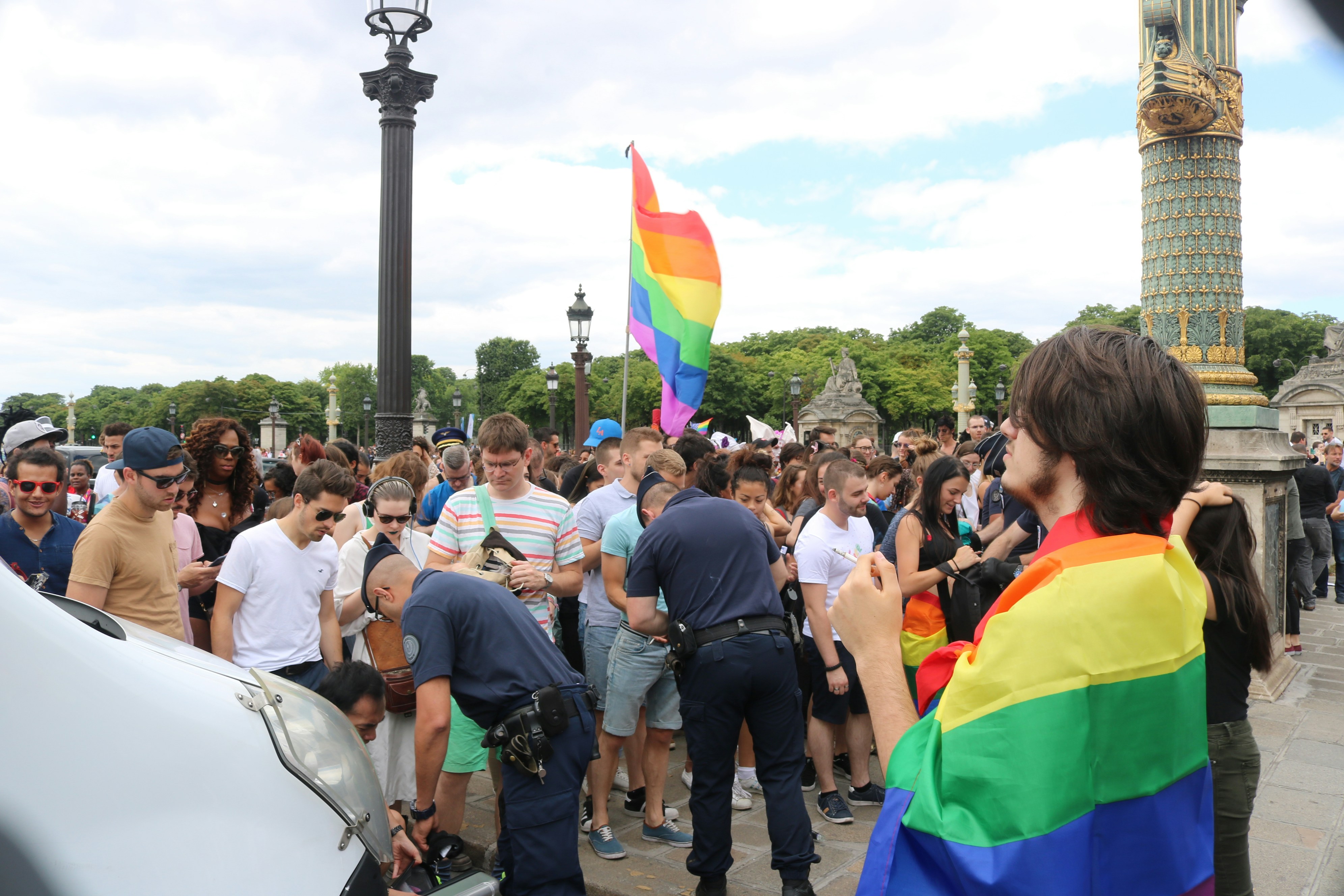 Multidão com bandeira arco-íris em um evento público.