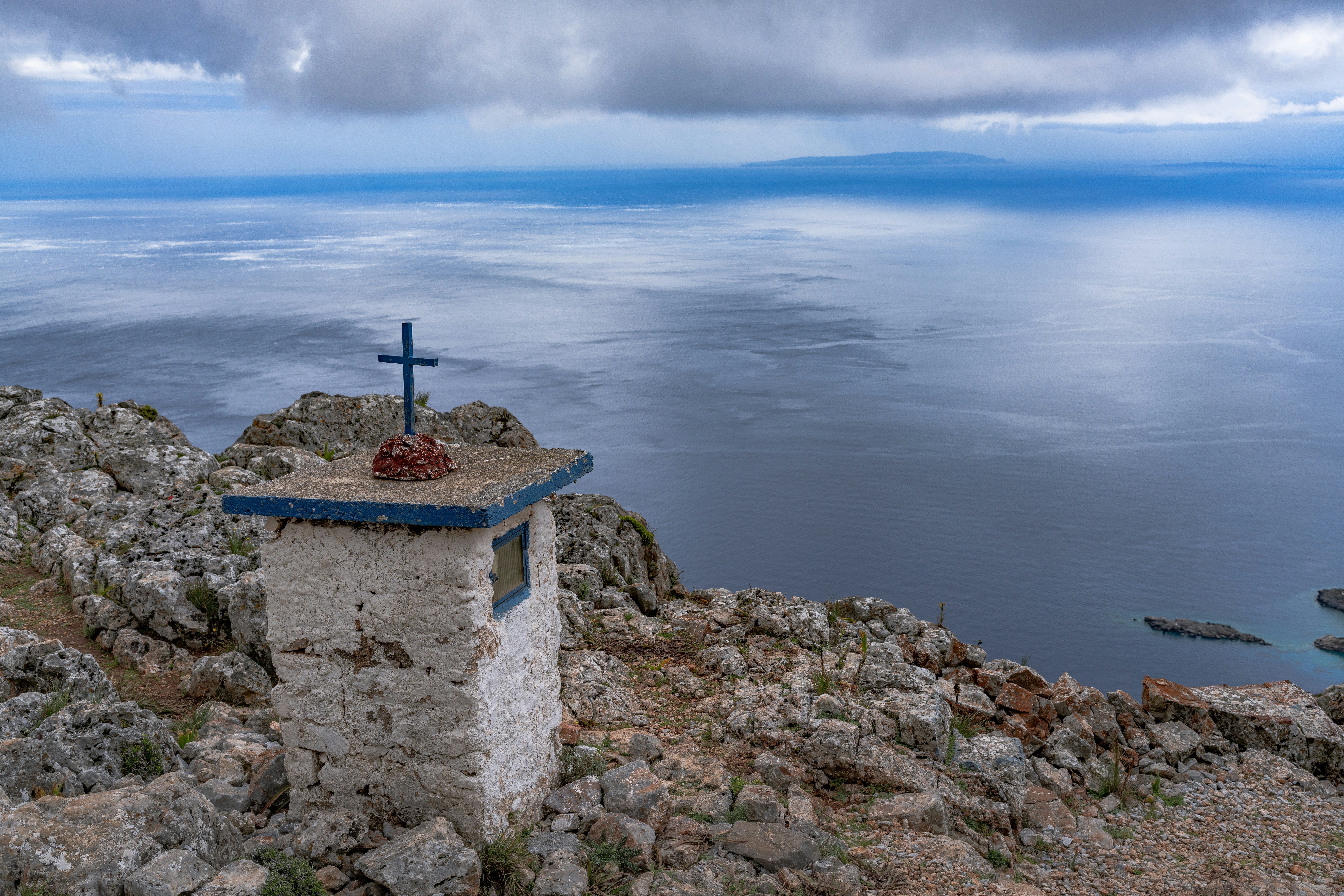 Kleiner Schrein mit Kreuz auf einer felsigen Klippe mit Blick auf das Meer