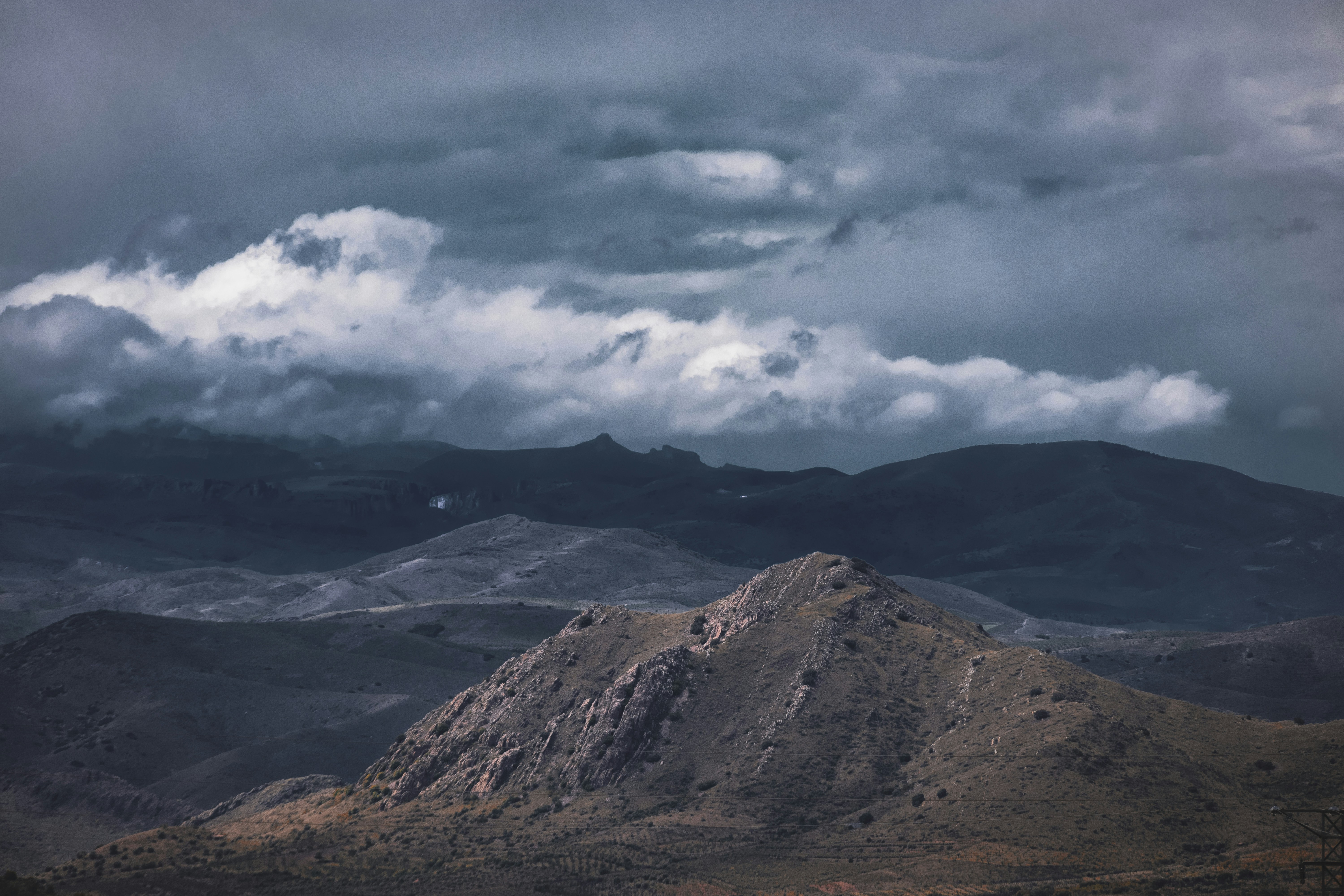 Dramatic mountain landscape under stormy, cloudy skies.