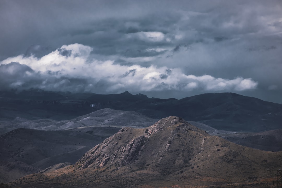 Dramatic mountain landscape under stormy, cloudy skies.