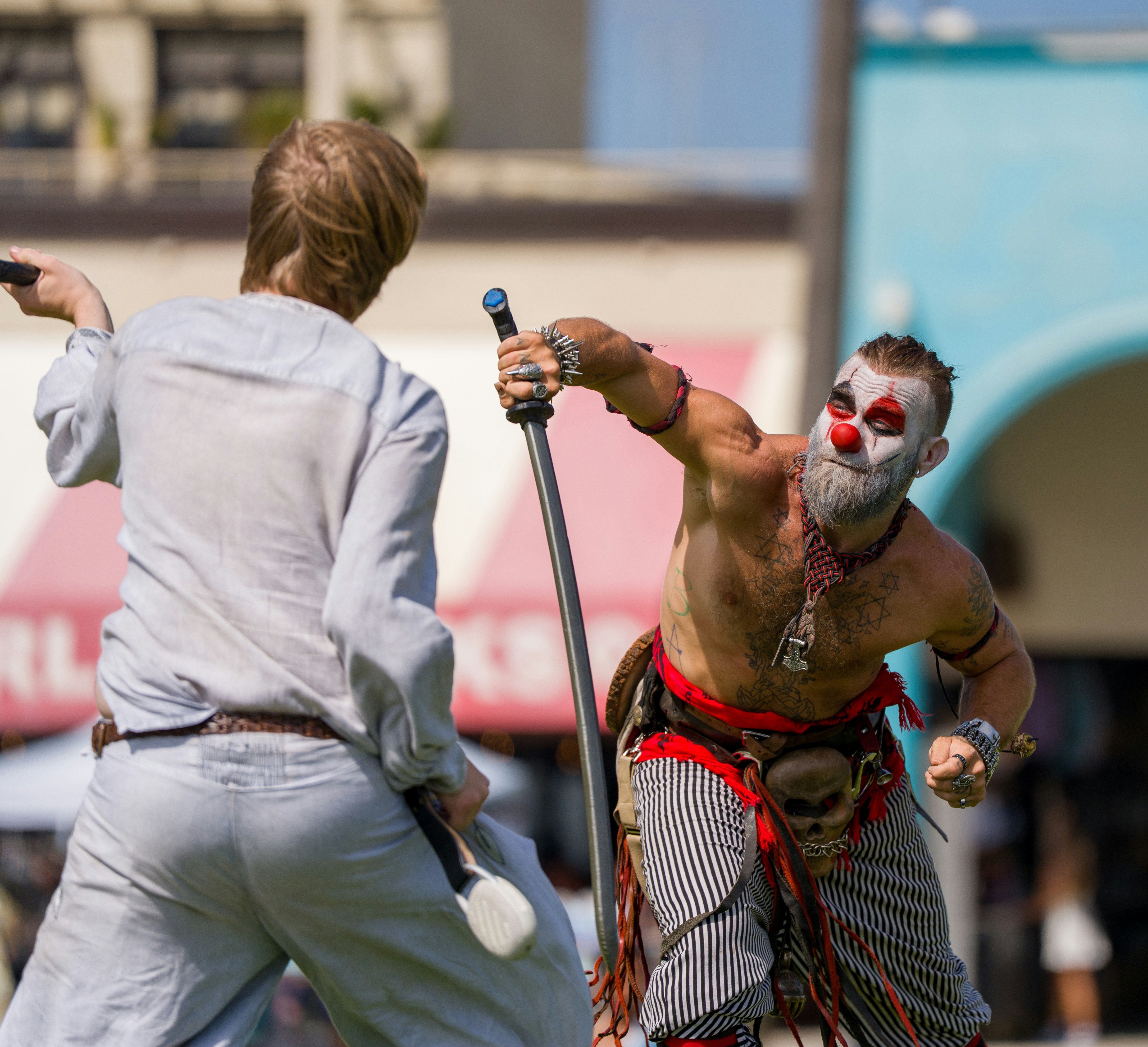 Clown with sword fights person in light clothing