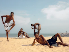 Four young men posing on a sandy beach