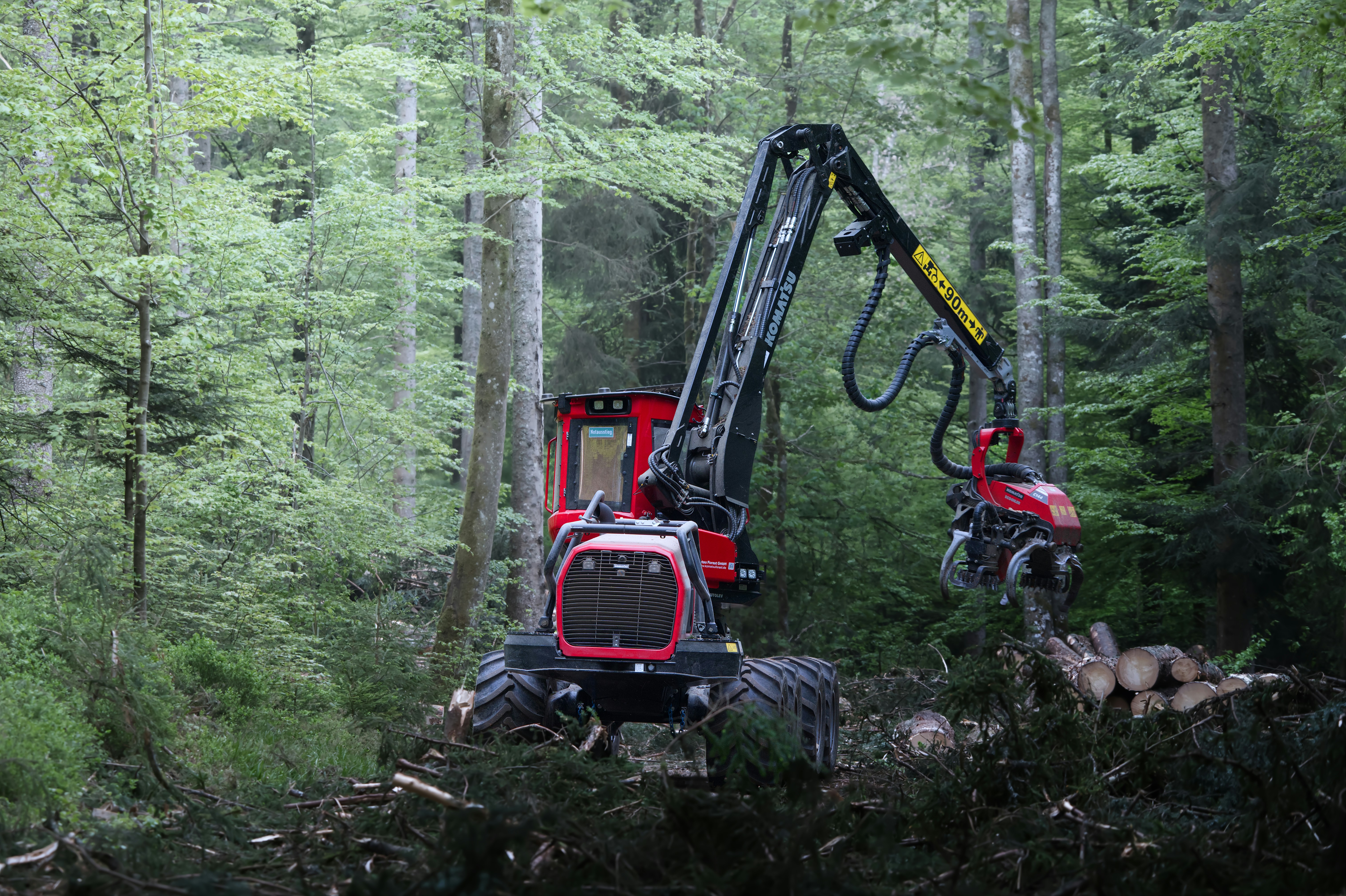 Una máquina de tala roja en un bosque denso