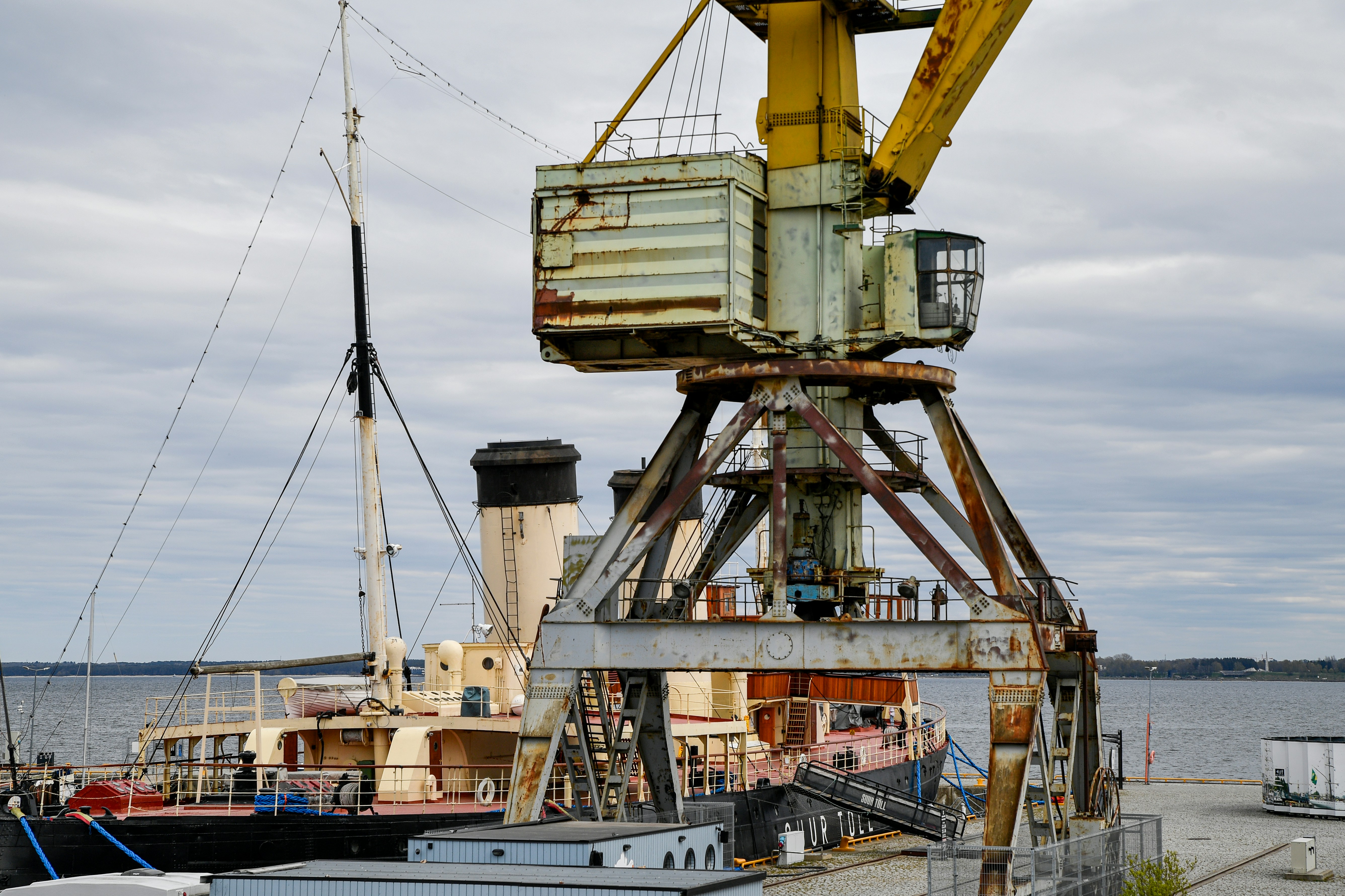 Old crane and ship docked at the harbor.