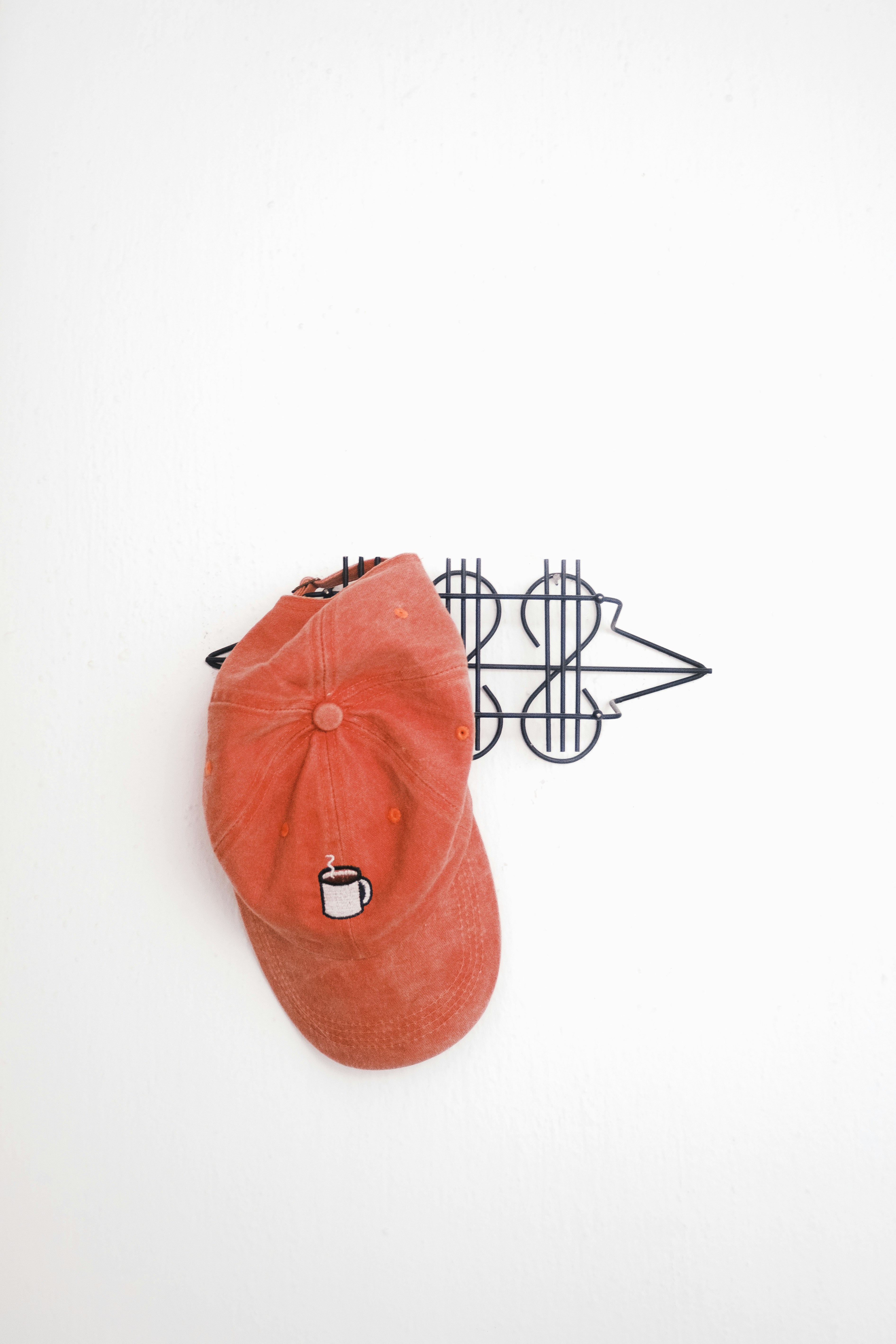 Cappello da baseball arancione con ricamo in tazza da caffè è appeso al gancio