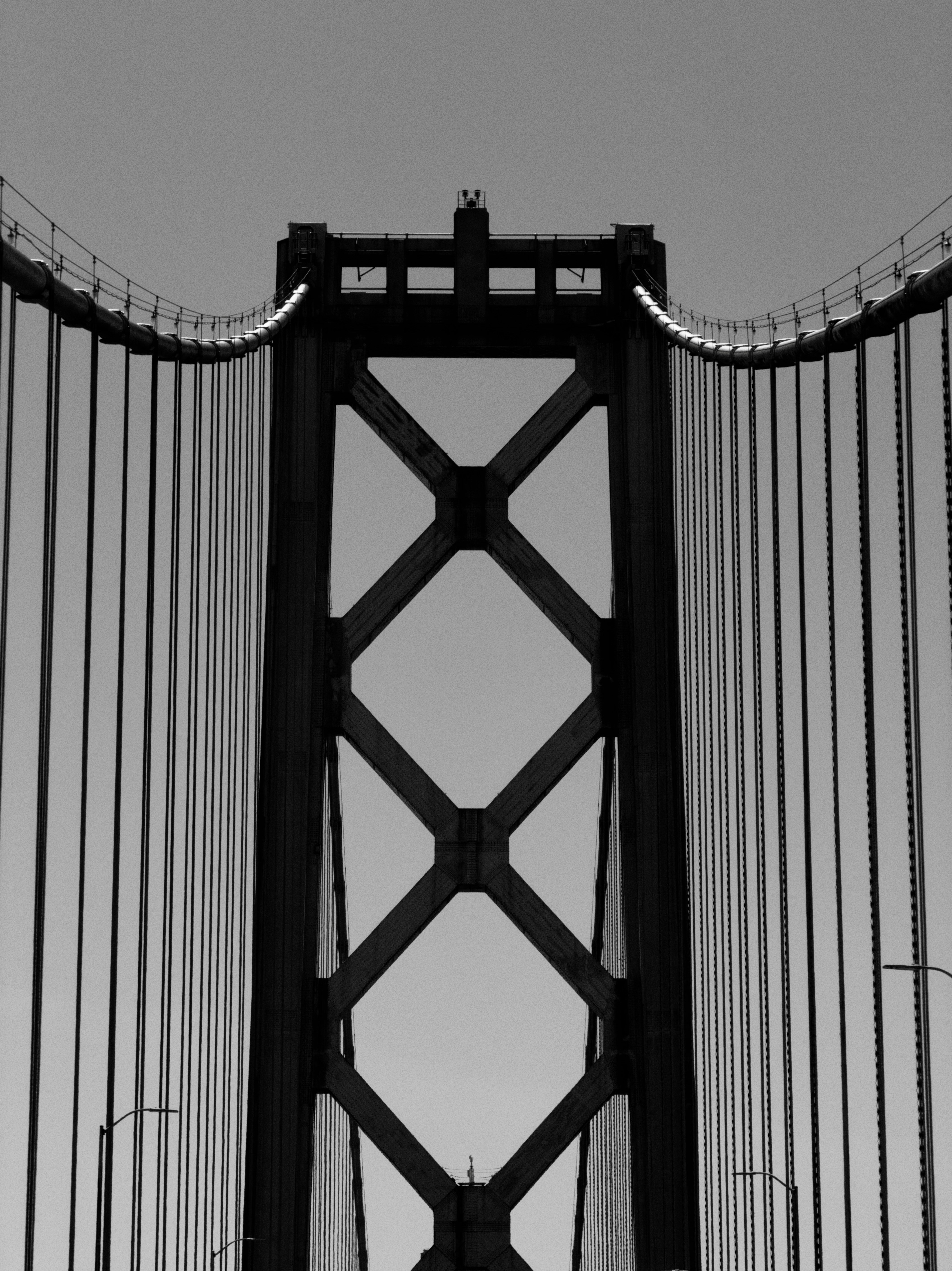 A black and white view of a suspension bridge tower