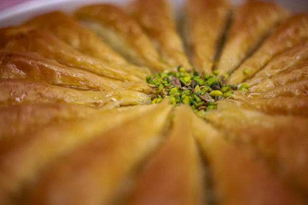 Golden Turkish baklava topped with chopped pistachios