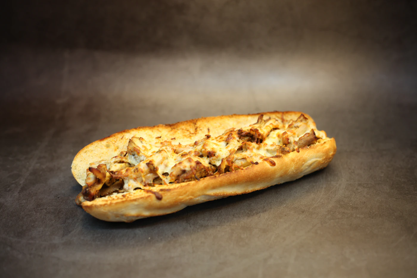 Toasted steak sandwich filled with sliced beef, melted cheese, peppers, and onions