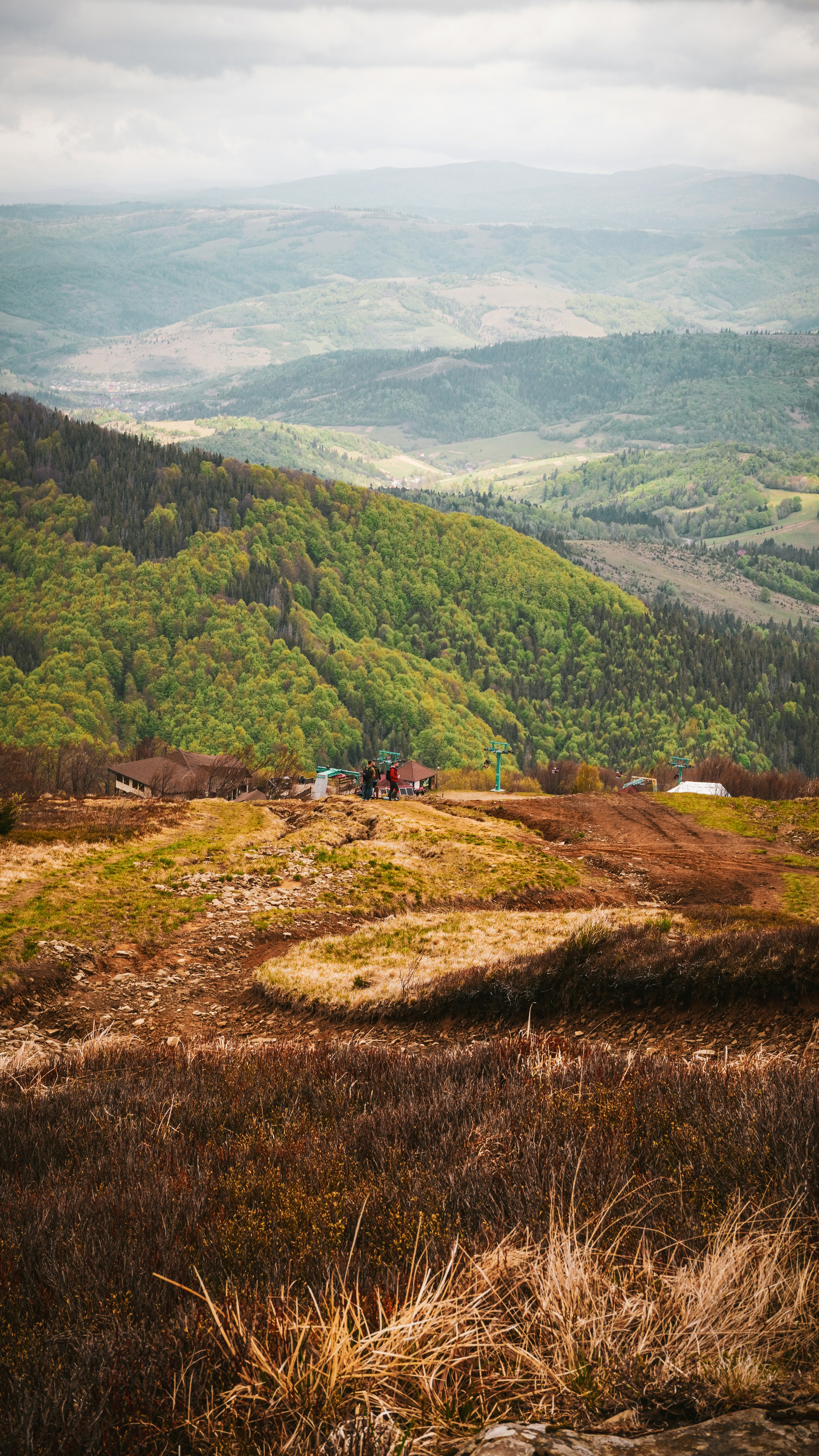 Paesaggio montuoso con edifici sparsi e foreste verdi.