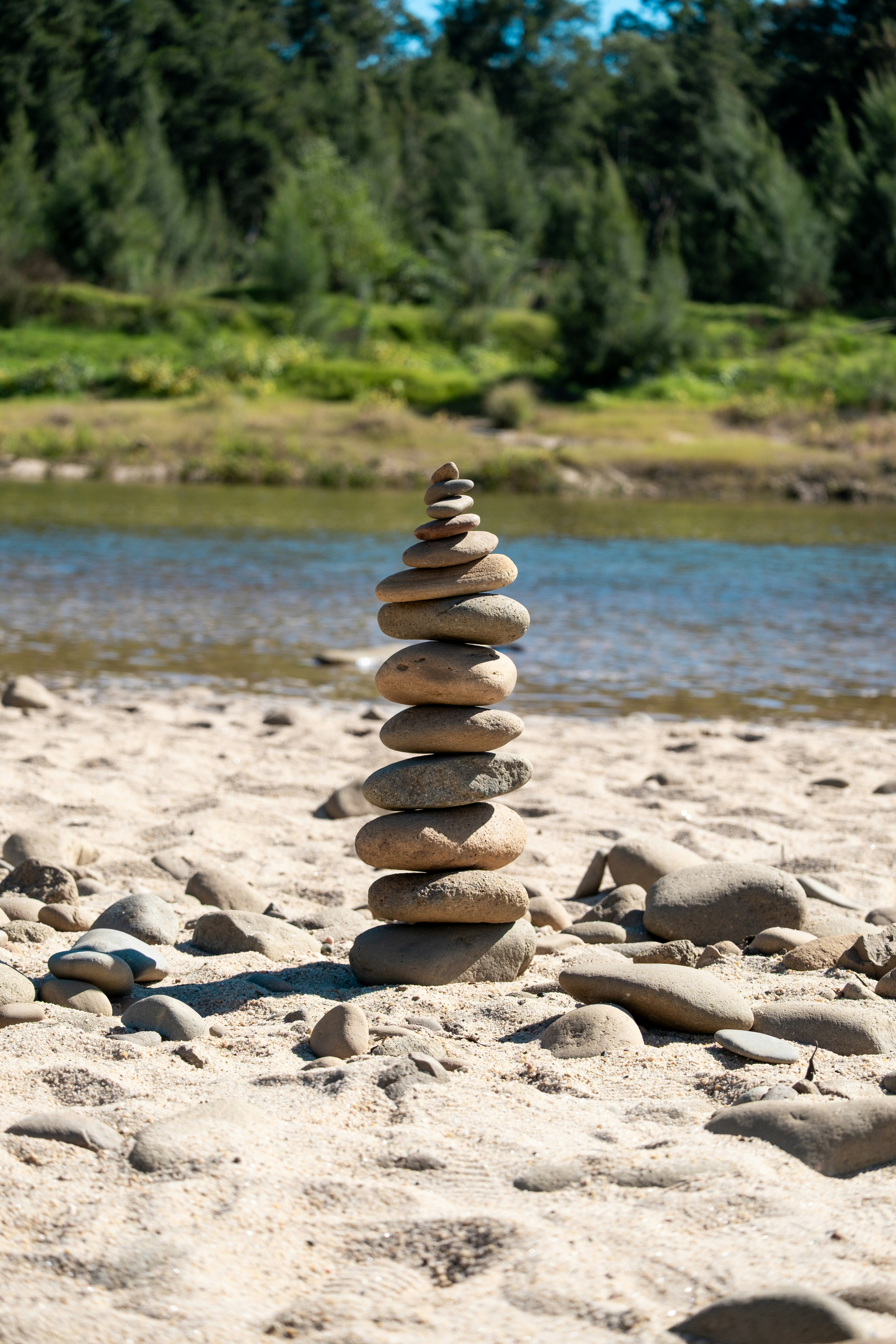 Pila di pietre equilibrate su una riva sabbiosa del fiume
