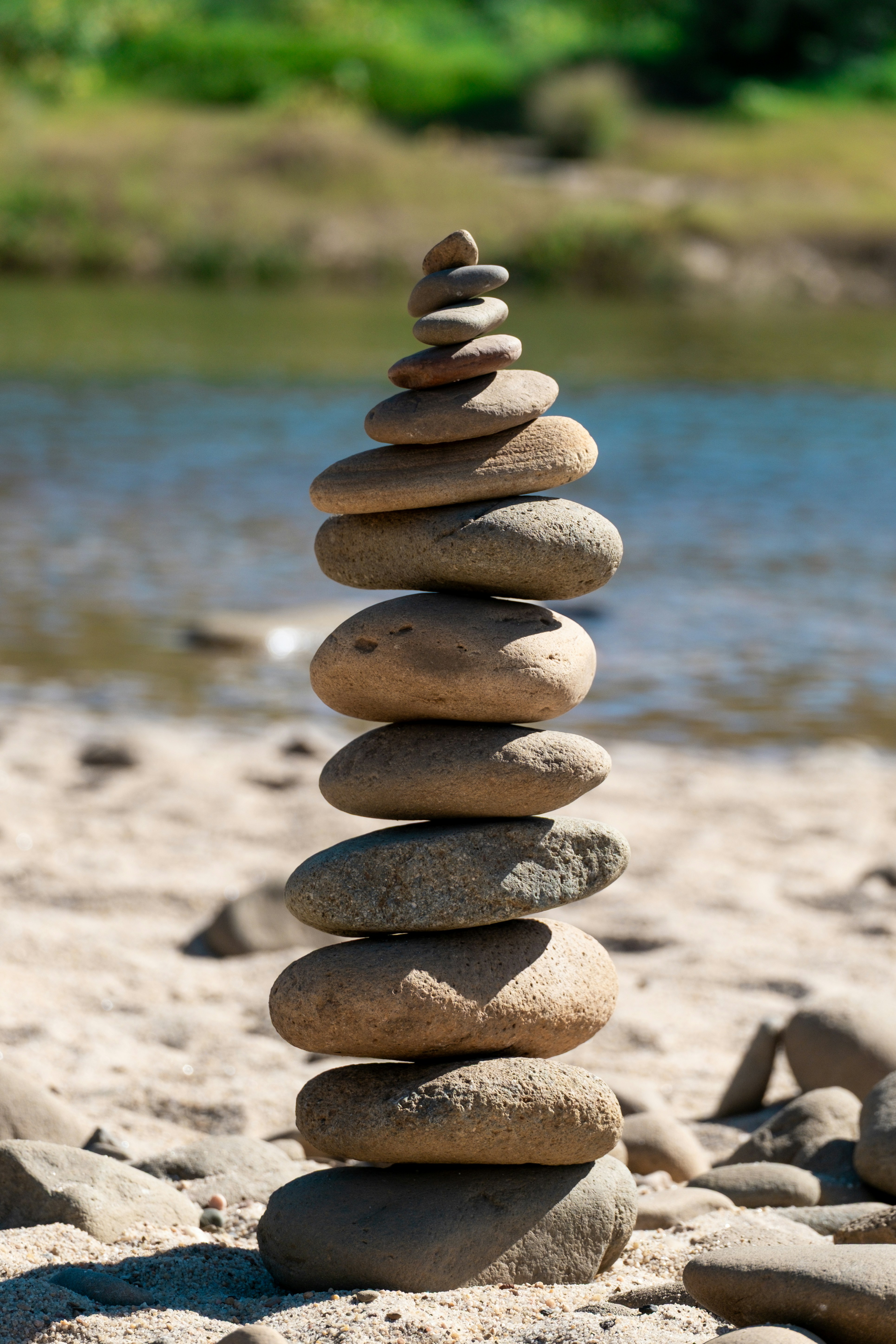 Pila di pietre equilibrate su una riva sabbiosa del fiume.