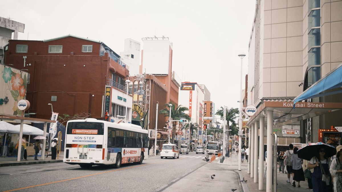 那霸國際通上行駛的路線公車，兩側是商店與行人
