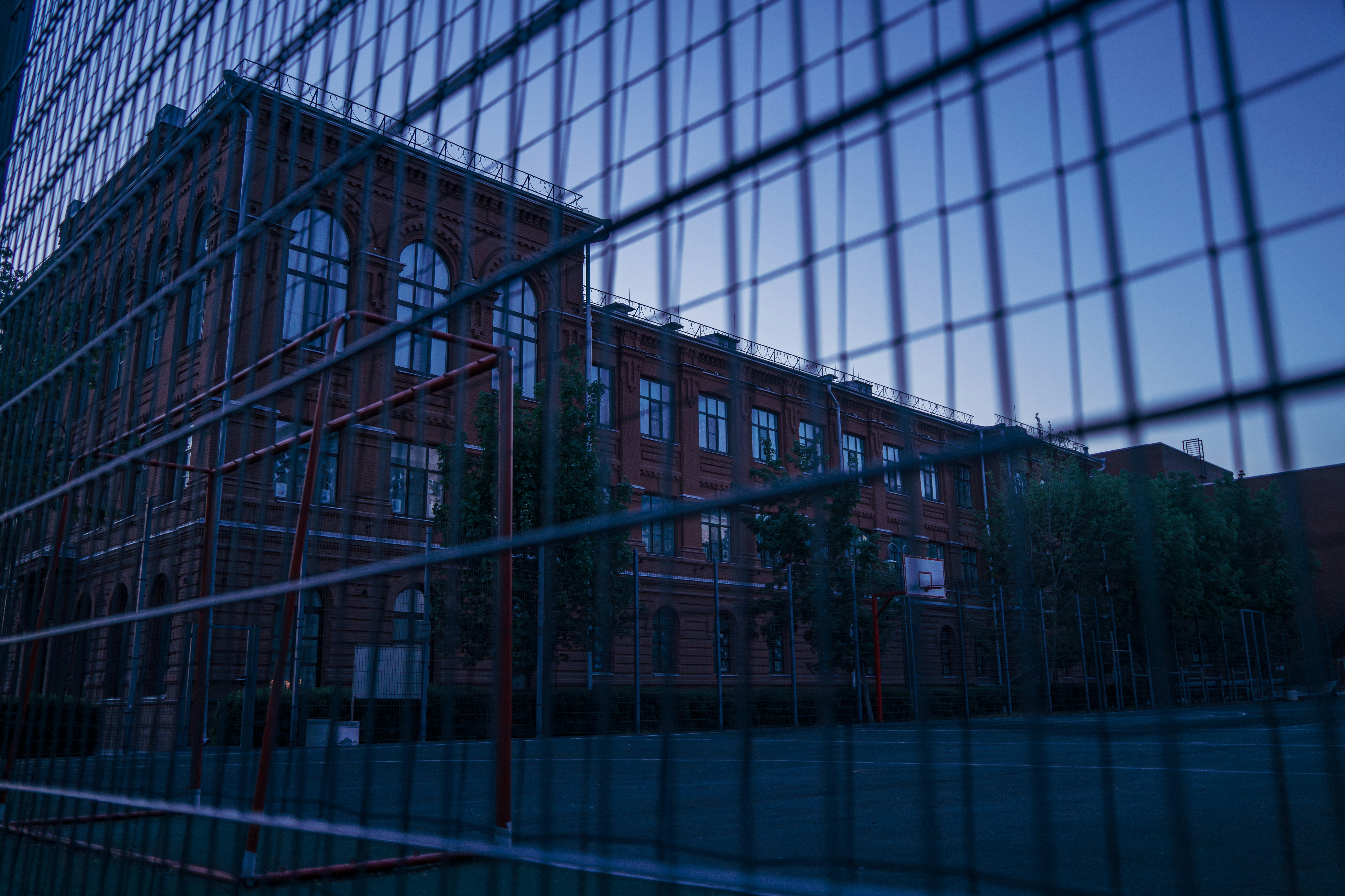 Brick building seen through a metal fence at dusk
