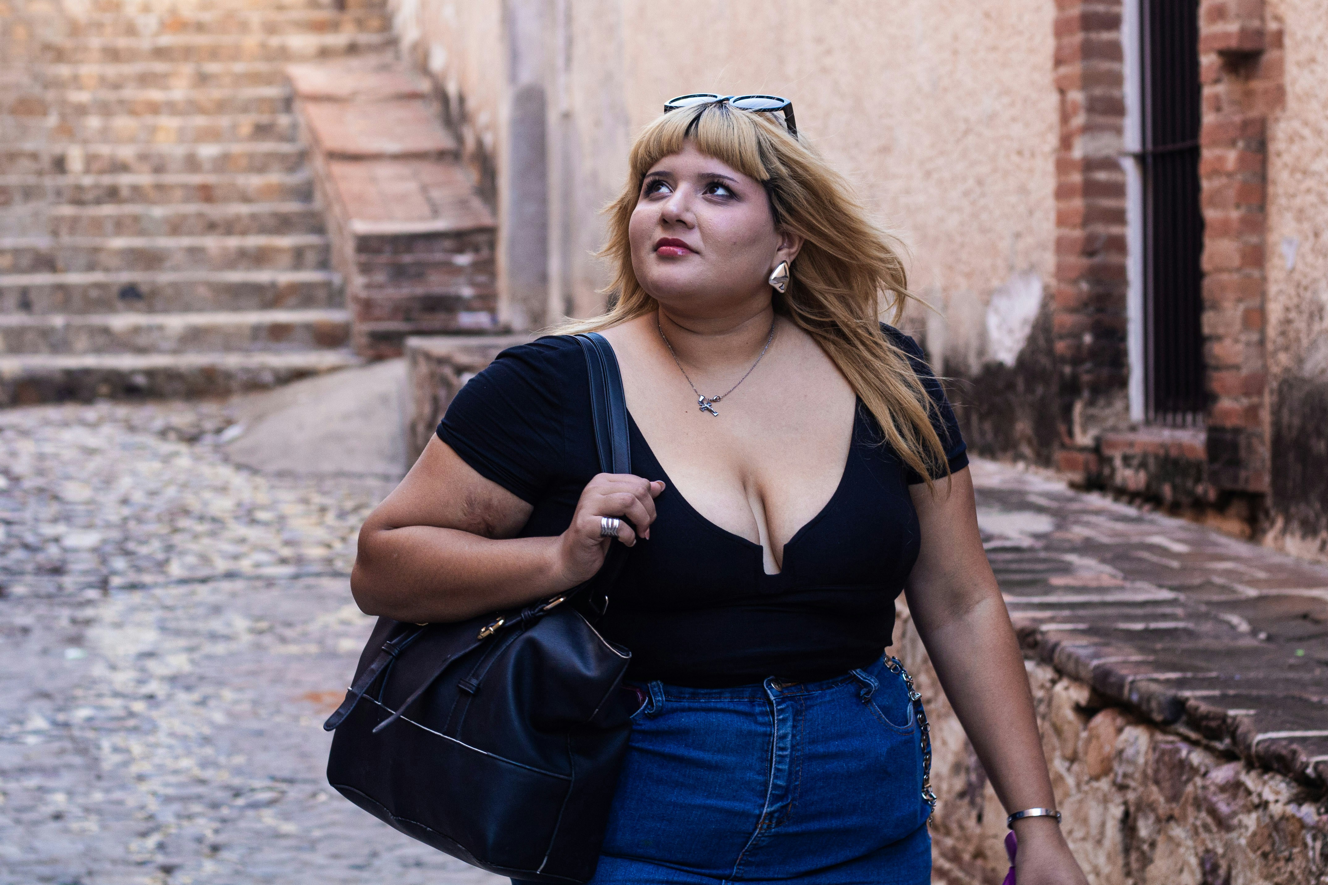 A woman walks down a cobblestone street.