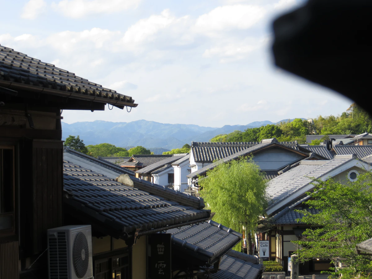 Traditional Japanese tiled rooftops with mountain views in a Japanese hillside town